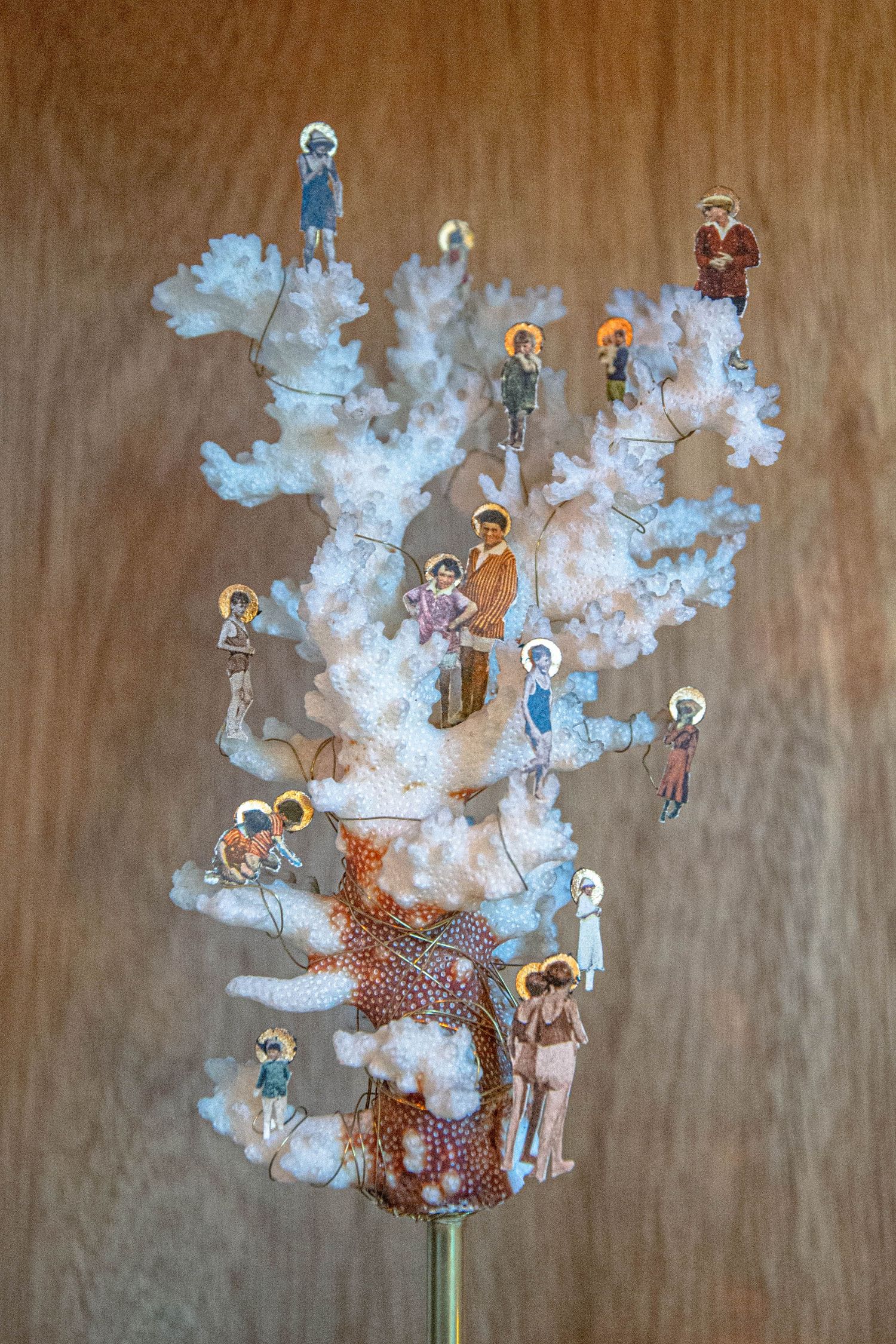 Sculpture décorative représentant des figures religieuses miniatures auréolées sur un arbre blanc évoquant le corail, le tout sur un fond;