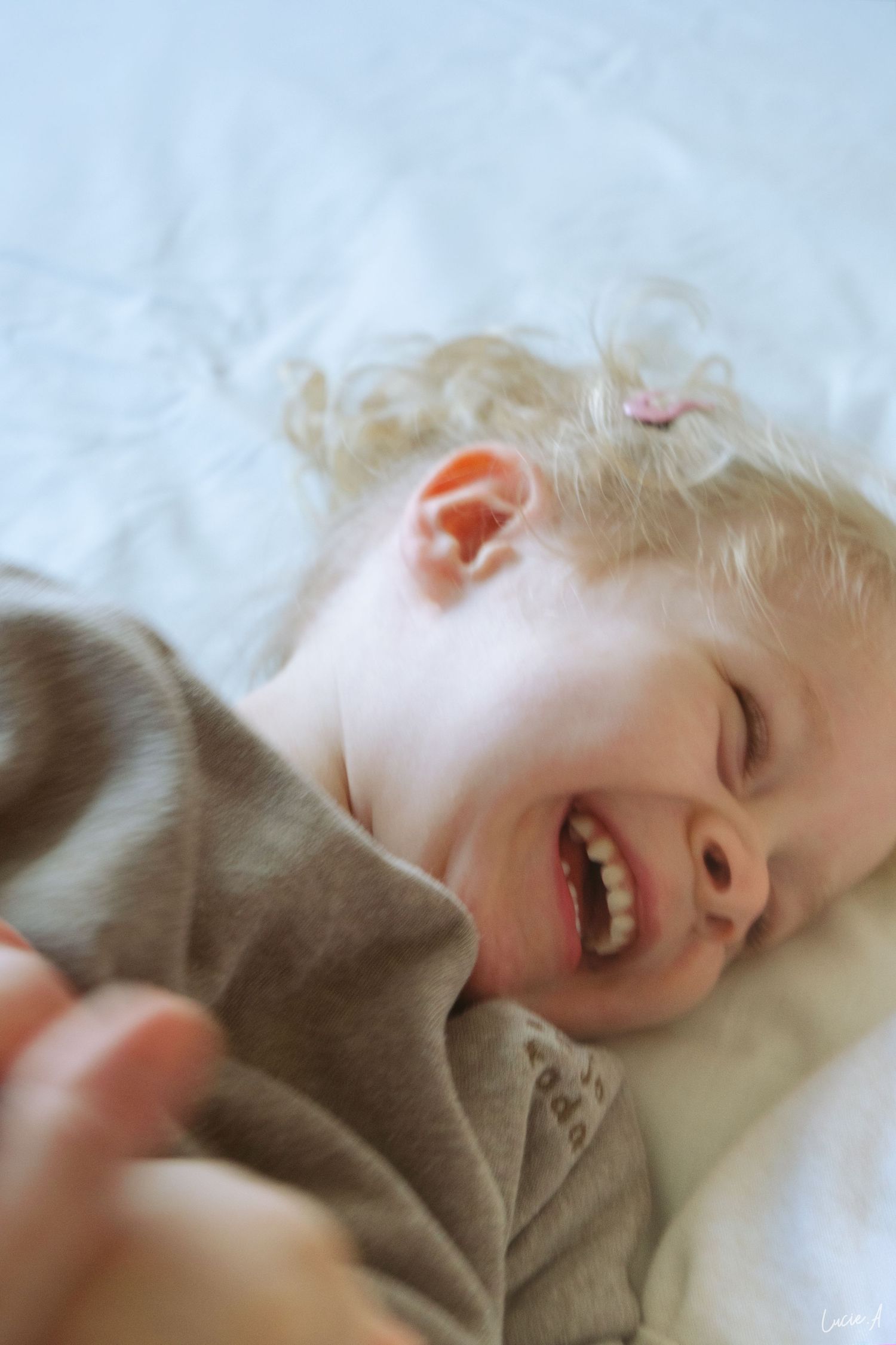 Portrait d'une petite fille blonde souriant au éclat face à une lumière douce et naturelle