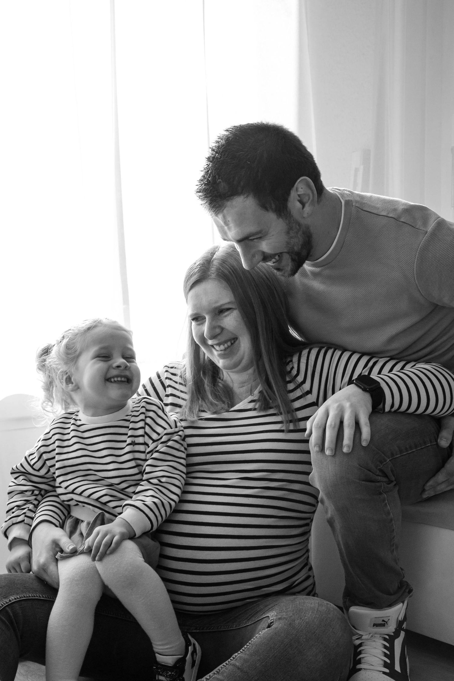 Portrait famille noir et blanc d'une séance grossesse, fille, père et mère sont assis et se regardent en souriant, prise à Ronchin