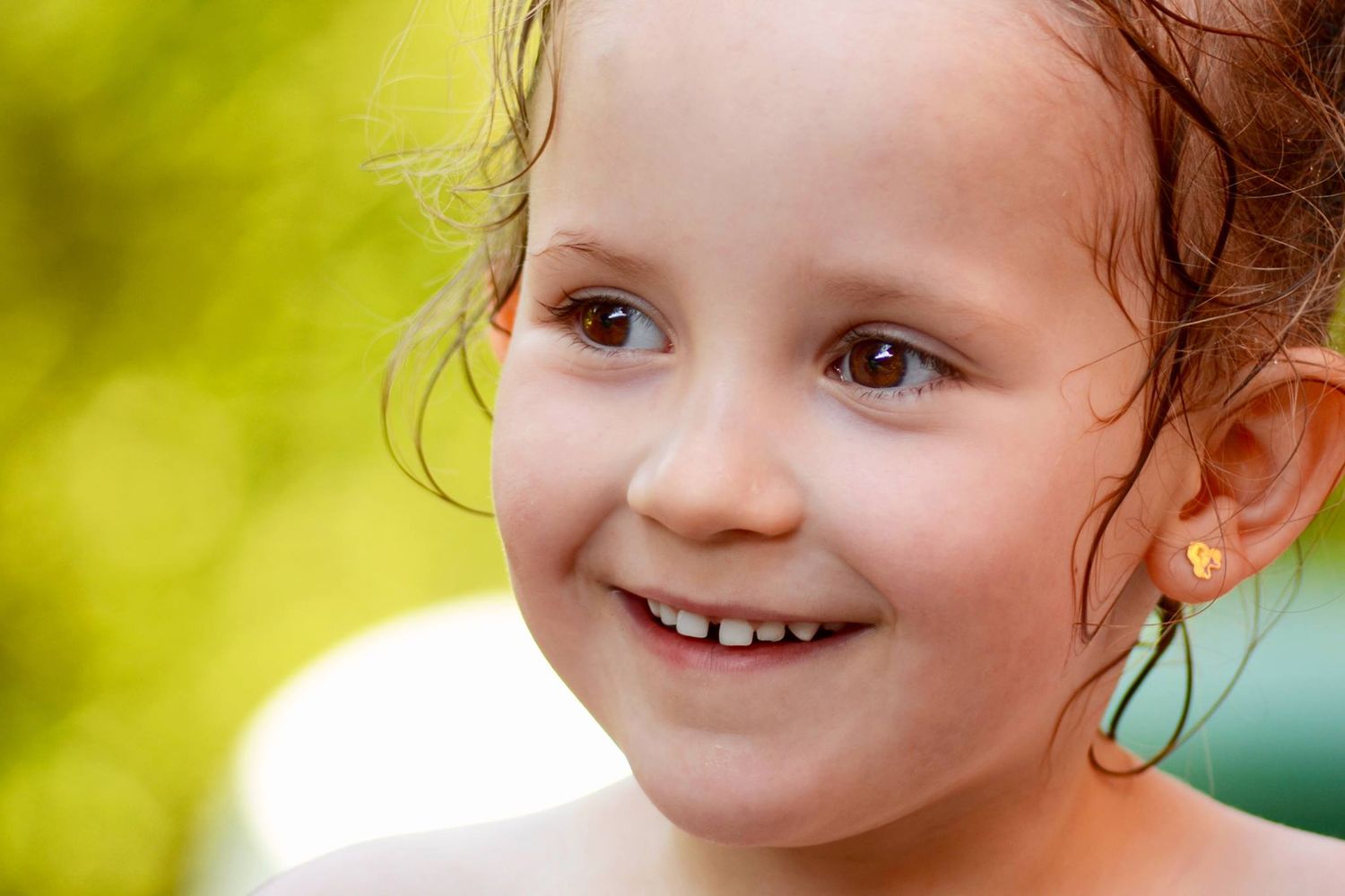 Portrait couleur gros blanc d'une petite fille souriant, regardant hors cadre, capté à Ronchin
