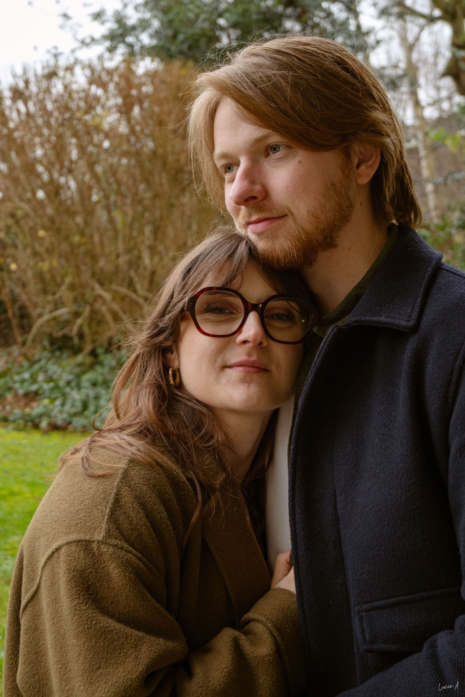 Portrait couleur couple, un homme regarde au loin avec sa compagne reposant sa tête contre sa poitrine, fait en extérieur à Ronchin