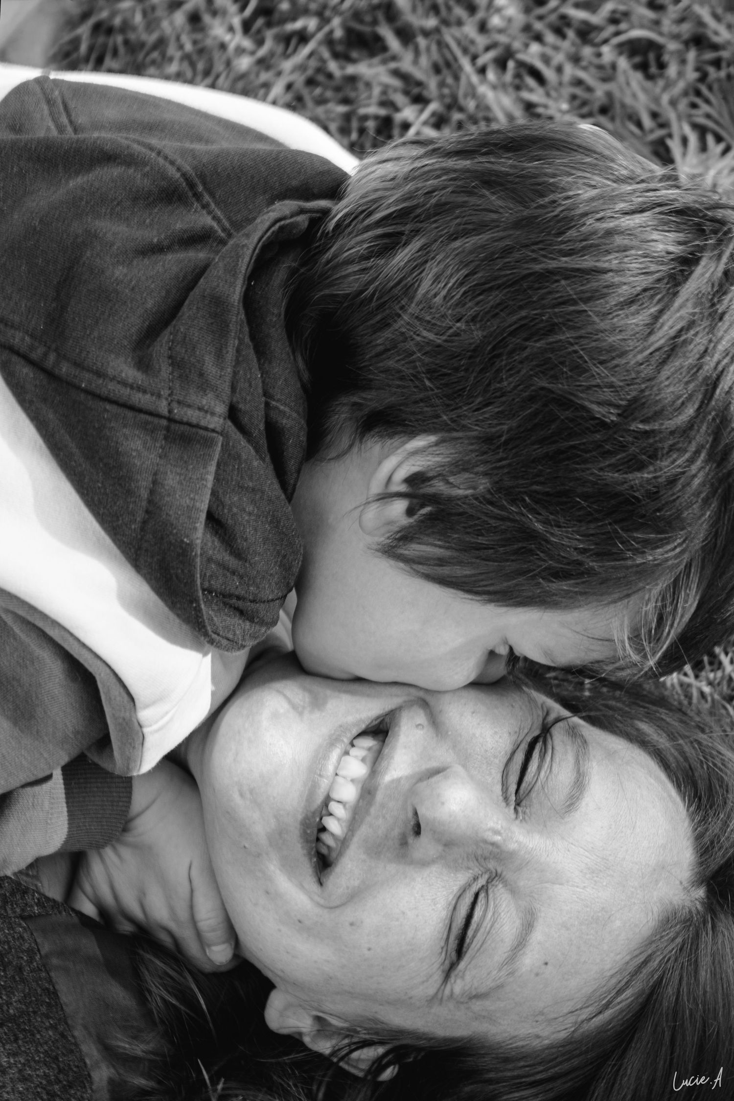 Portrait en noir et blanc d'une maman et de son fils allongés dans l'herbe se faisant un calin