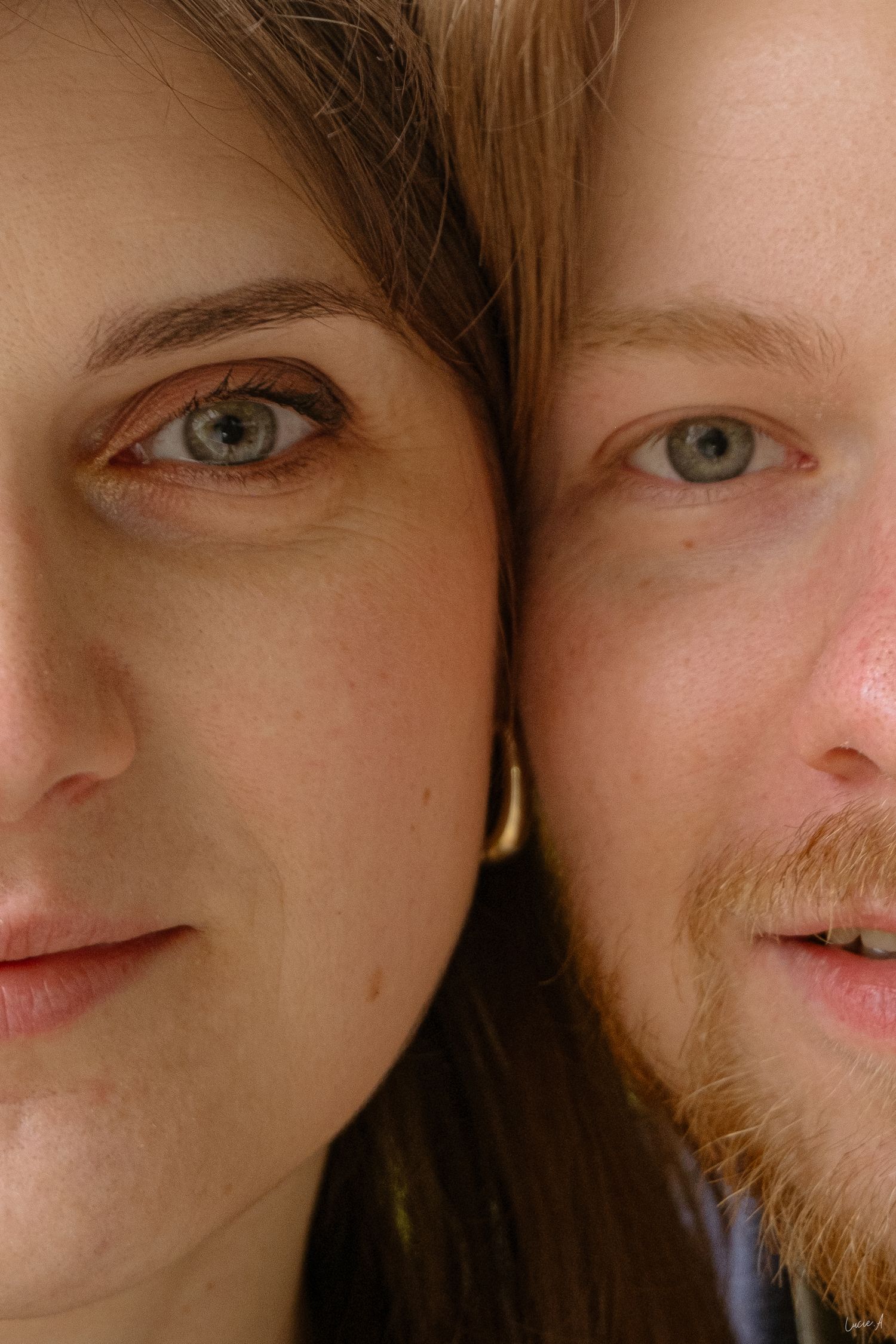 Portrait en gros plan d'un homme et d'une femme aux yeux bleu-vert et à la peau claire, posant joue contre joue.