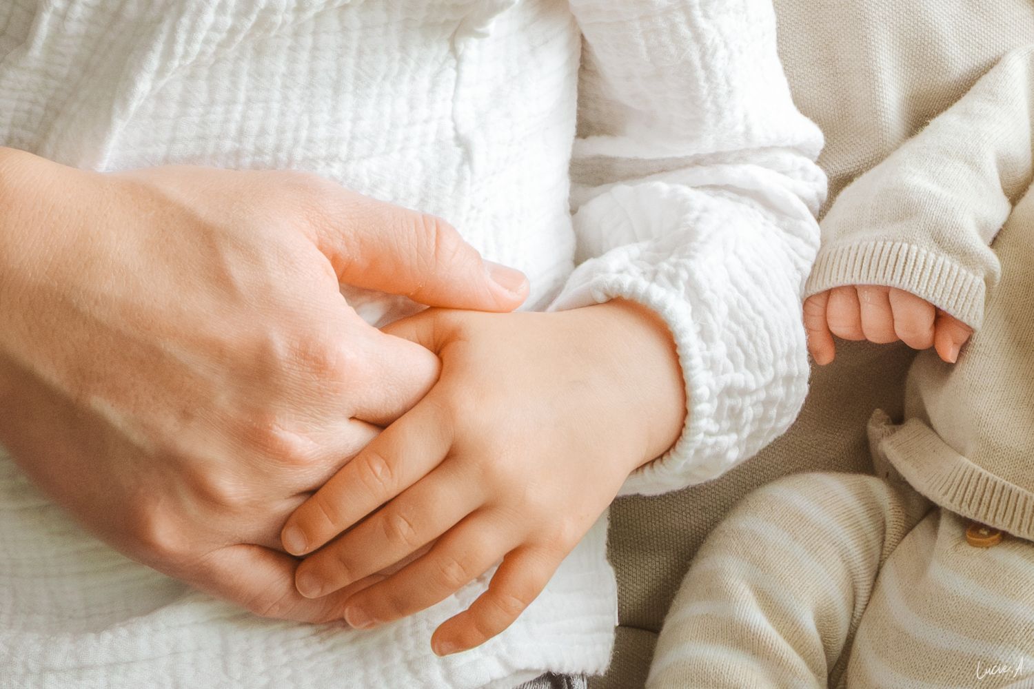Gros plan d’un parent tenant doucement la main d’un nouveau-né, symbolisant l’amour et la nouvelle parentalité.