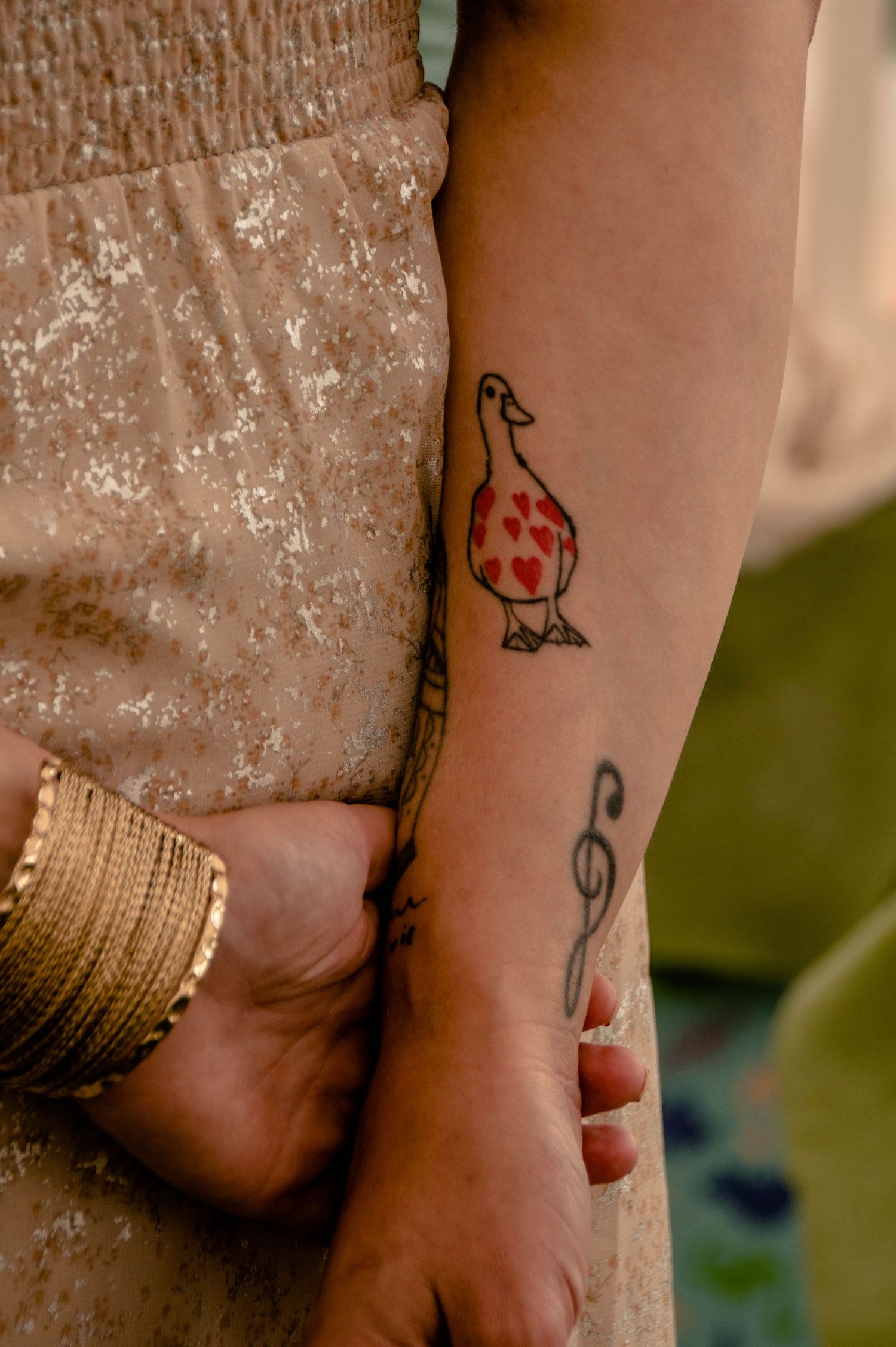 Gros plan couleur sur des bras tatoués croisés de dos, séance baptême