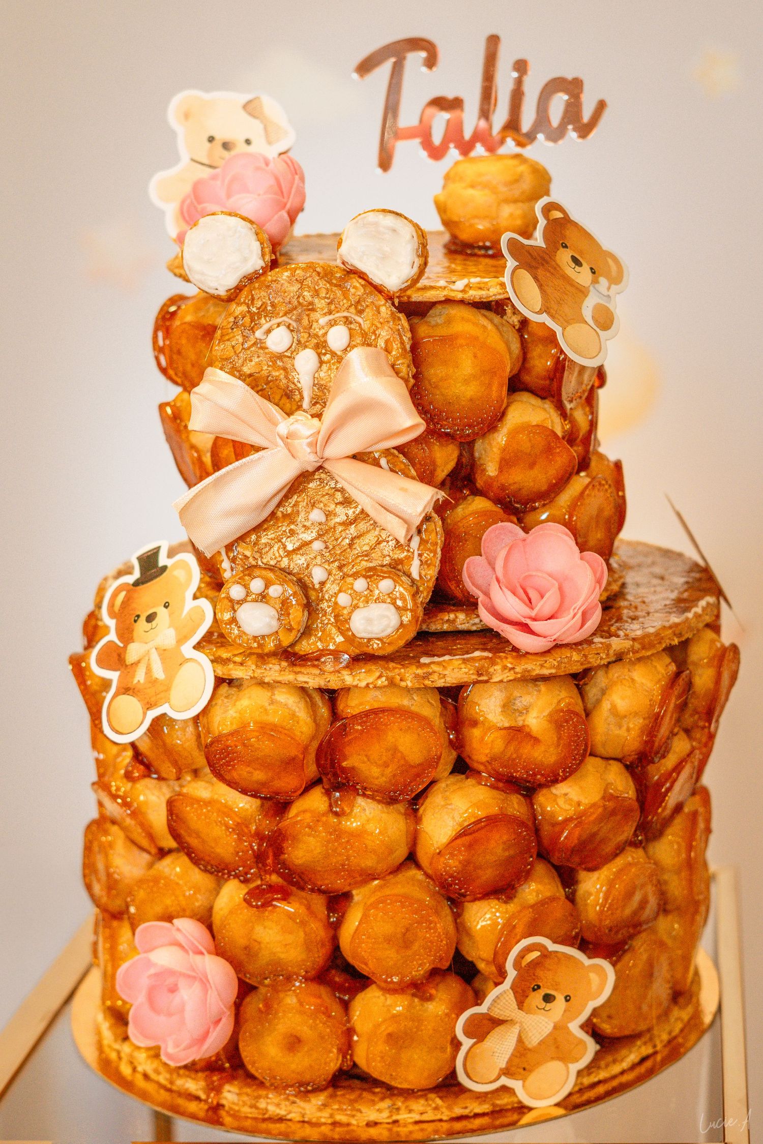 A croquembouche tower decorated with teddy bear cookies, pink roses, and a 