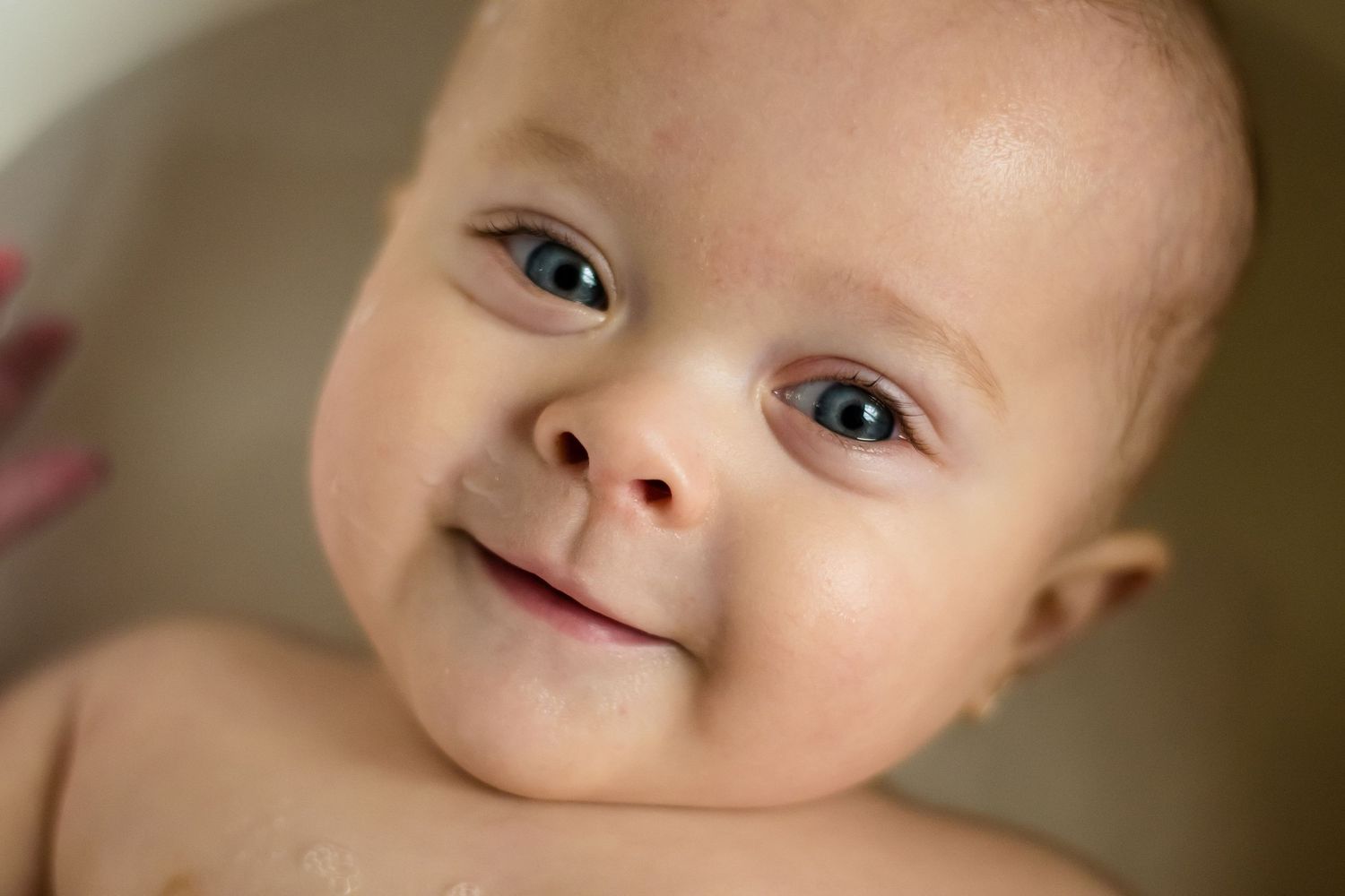 Portrait d’un bébé souriant en lumière naturelle, séance naissance à Ronchin