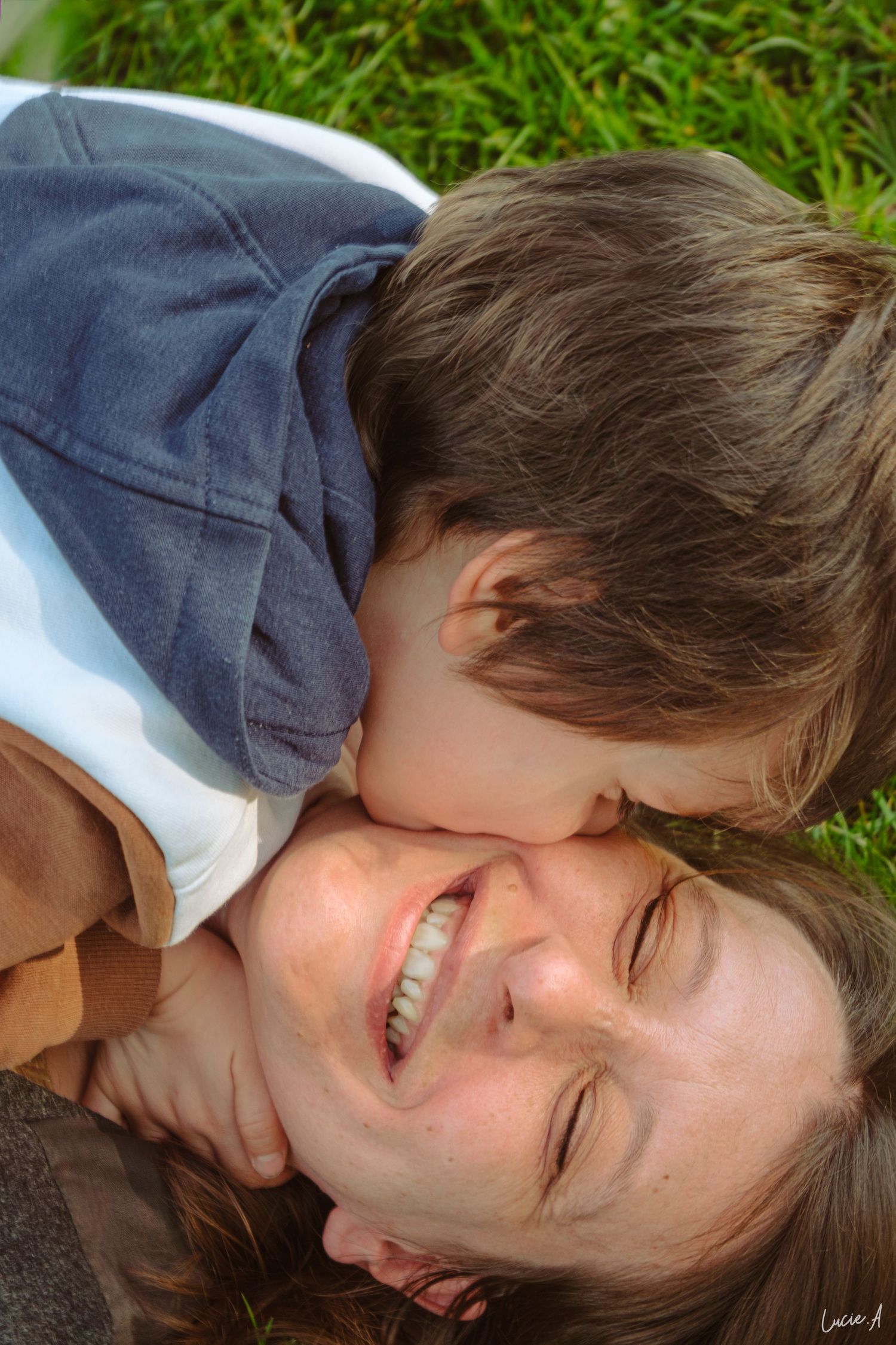 Portrait en couleur d'une maman et de son fils allongés dans l'herbe se faisant un calin
