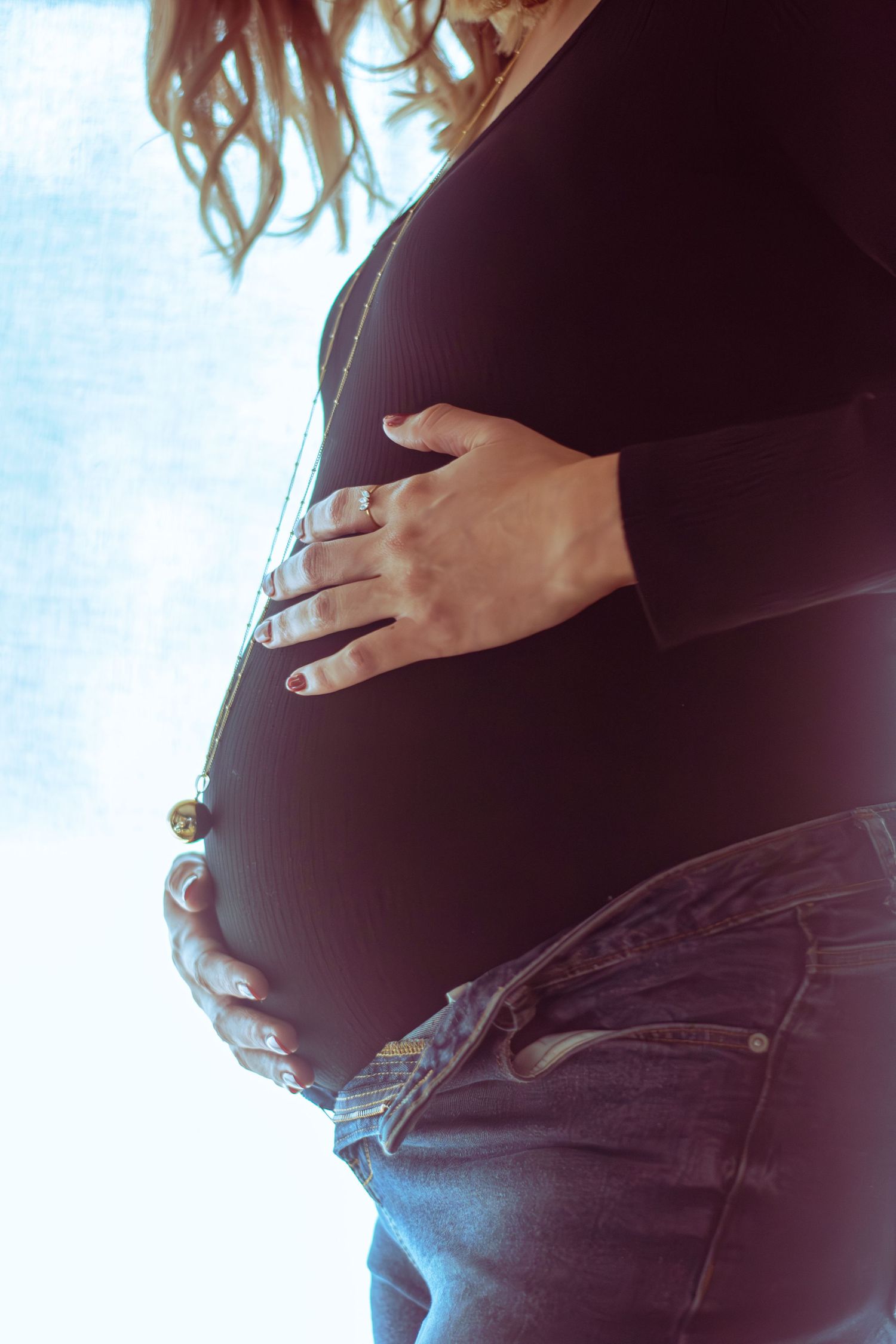 Portrait couleur grossesse, gros plan de profil la mère enlaçant son ventre, capté à Ronchin