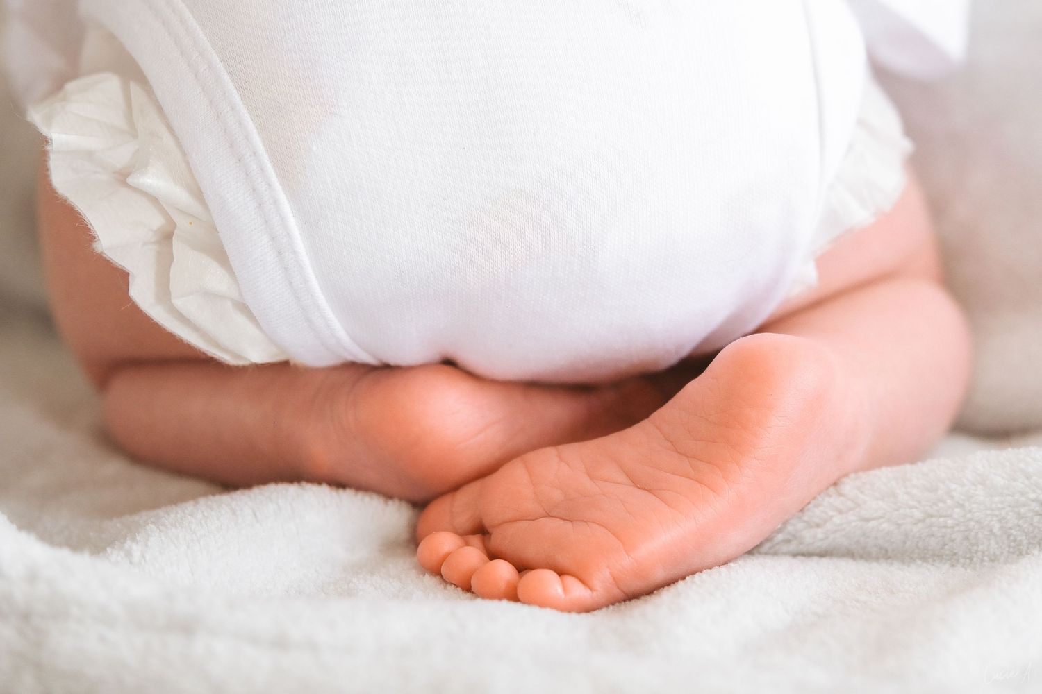 Gros plan sur les adorables petits pieds d'un bébé reposant sur une douce couverture blanche, portant une couche blanche.