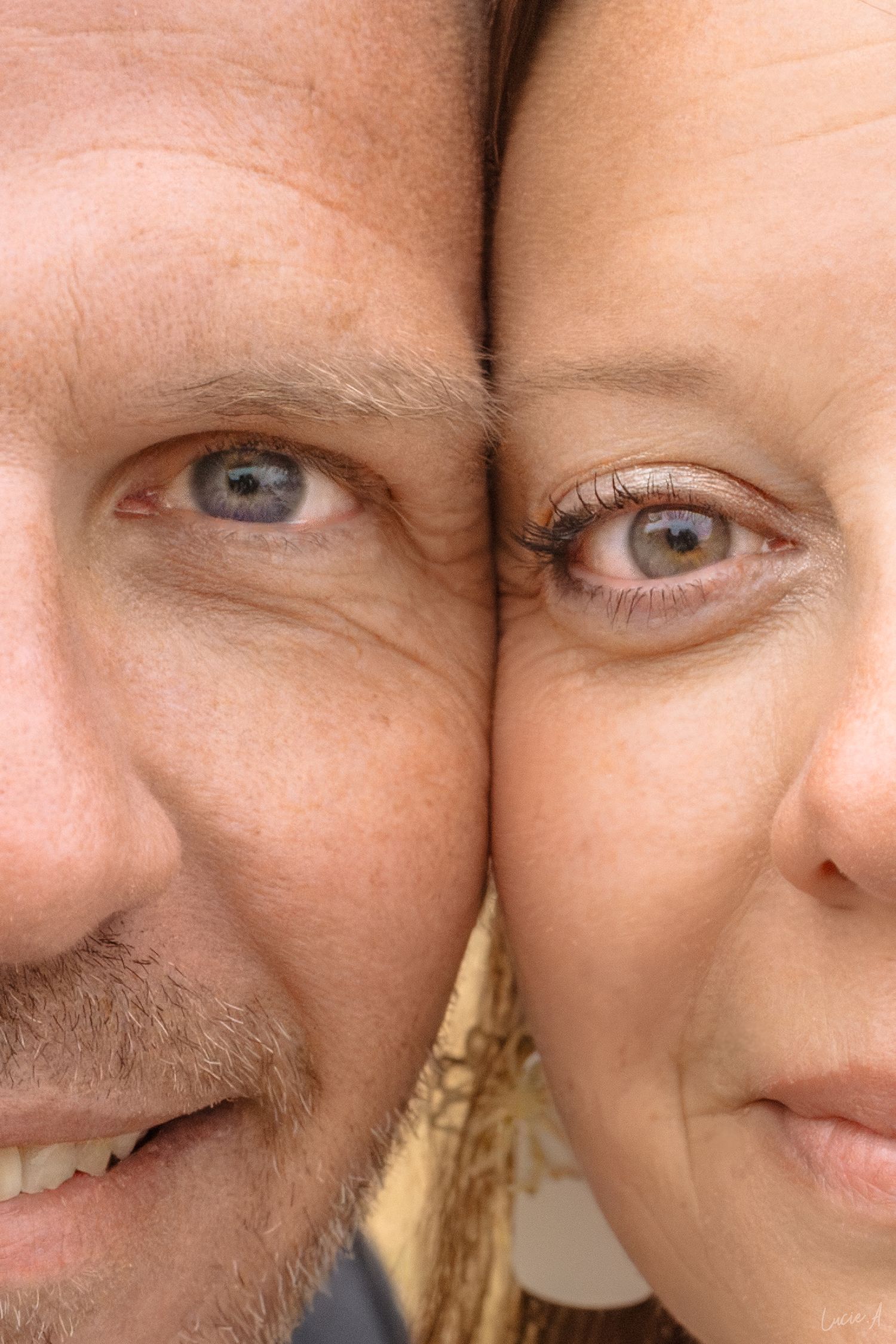 Portrait en gros plan d'un homme et d'une femme pressant leurs visages l'un contre l'autre, révélant des yeux bleus et bruns.