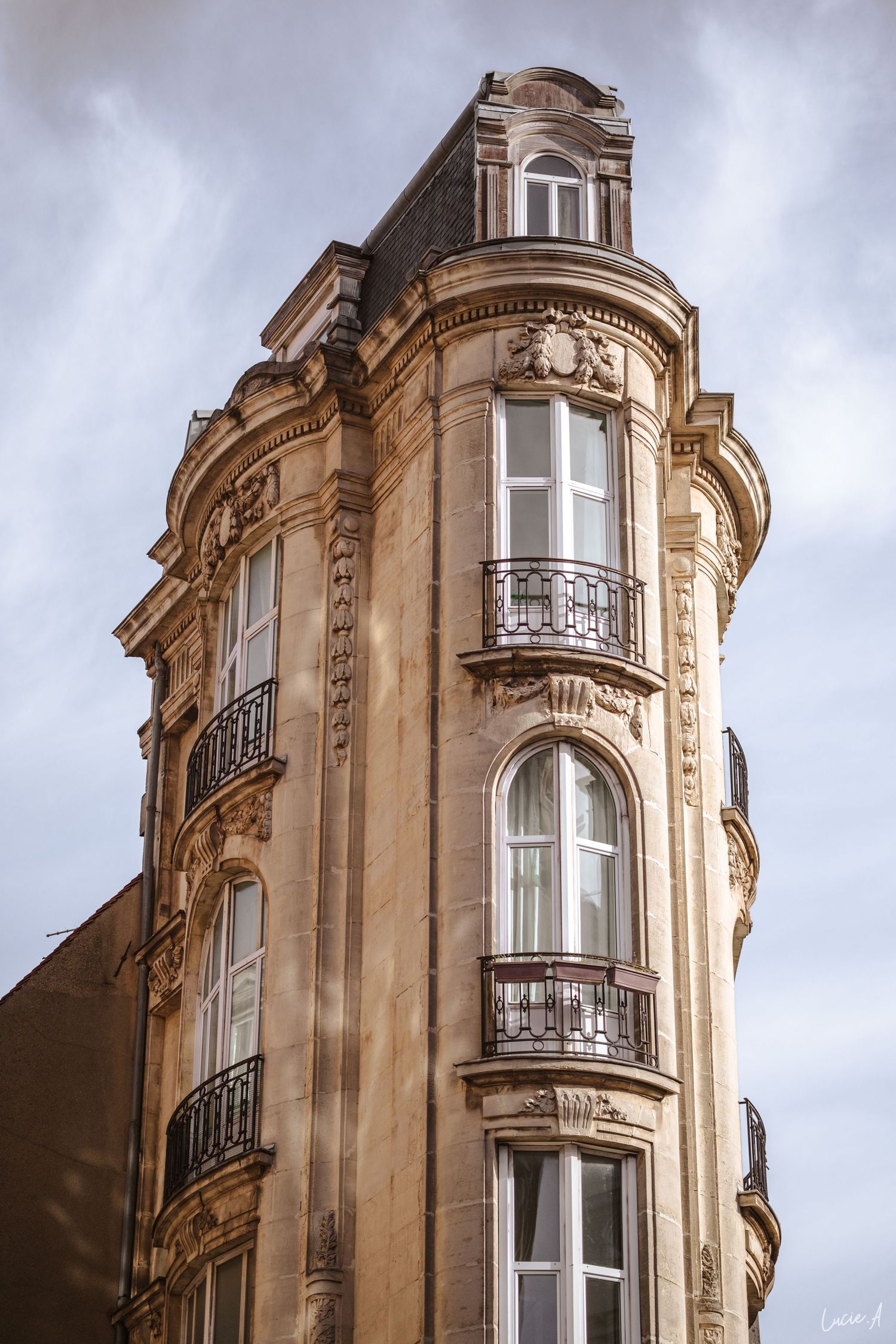Immeuble lillois classique de style haussmannien, angle de rue, avec façade en pierre ornée, balcons en fer forgé et toit mansardé, se déta