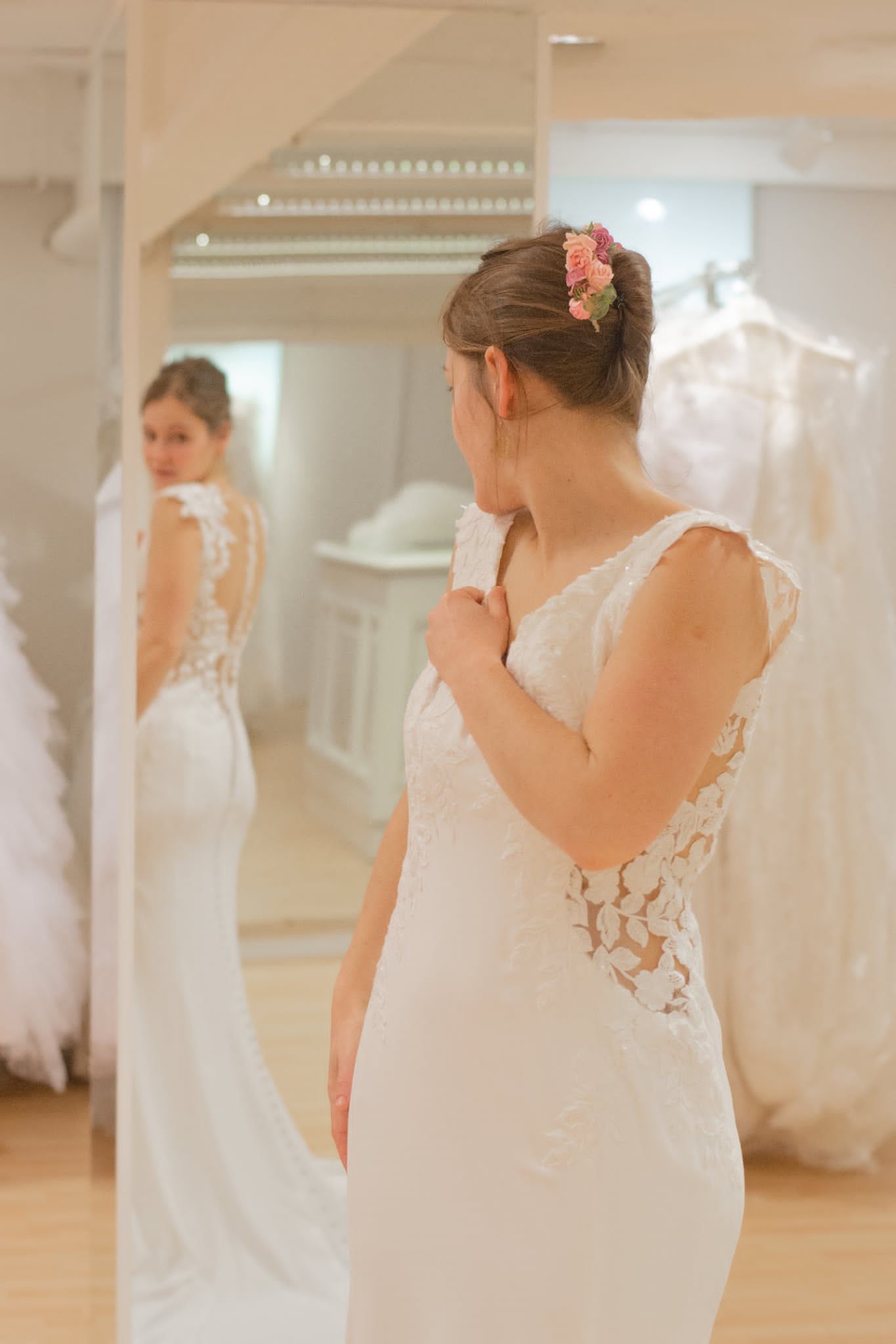 Une mariée essaie une élégante robe de mariée en dentelle blanche dans une boutique spécialisée, en admirant son reflet dans un miroir.