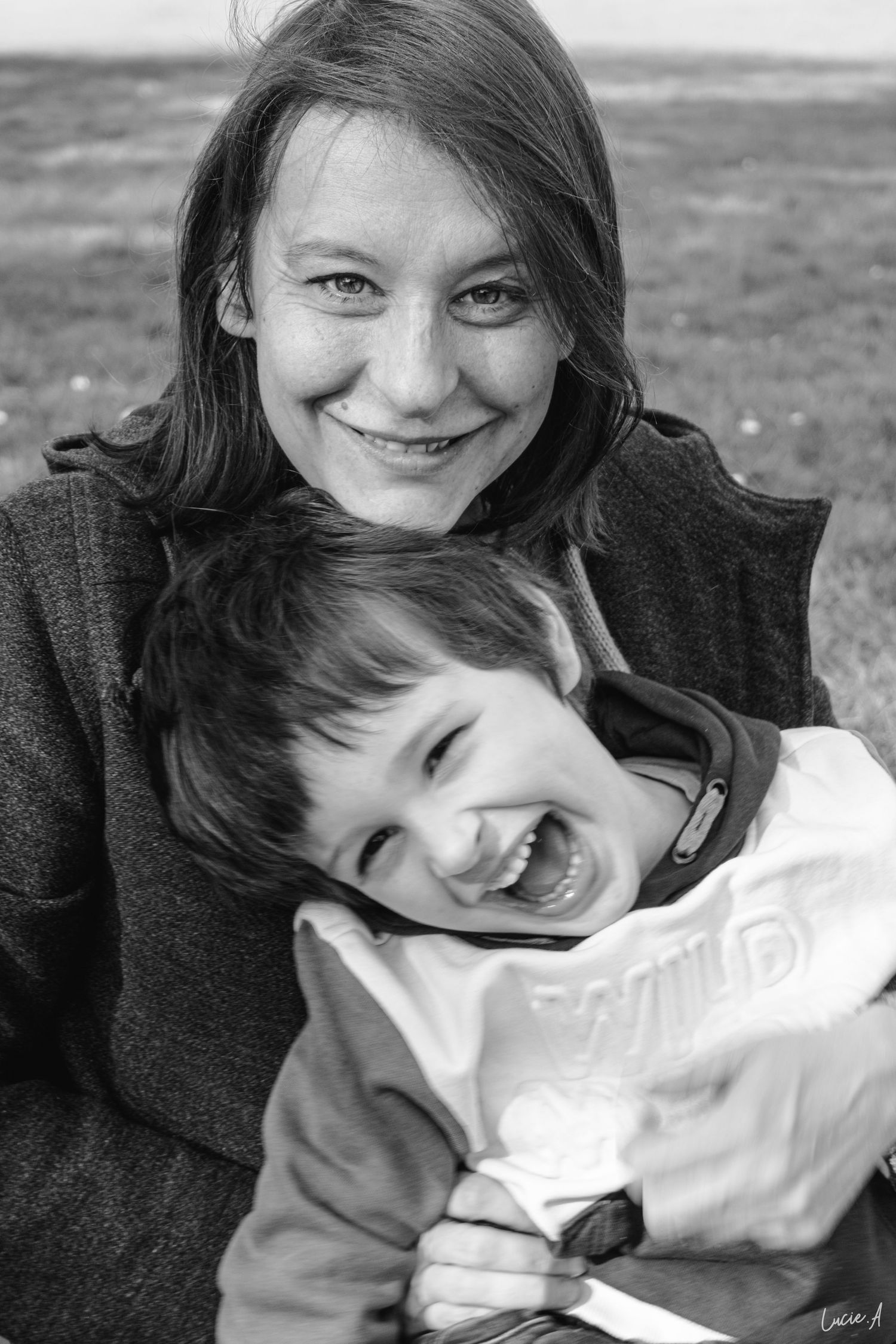 Portrait en noir et blanc d'une maman et de son fils se faisant un calin assis sur un banc