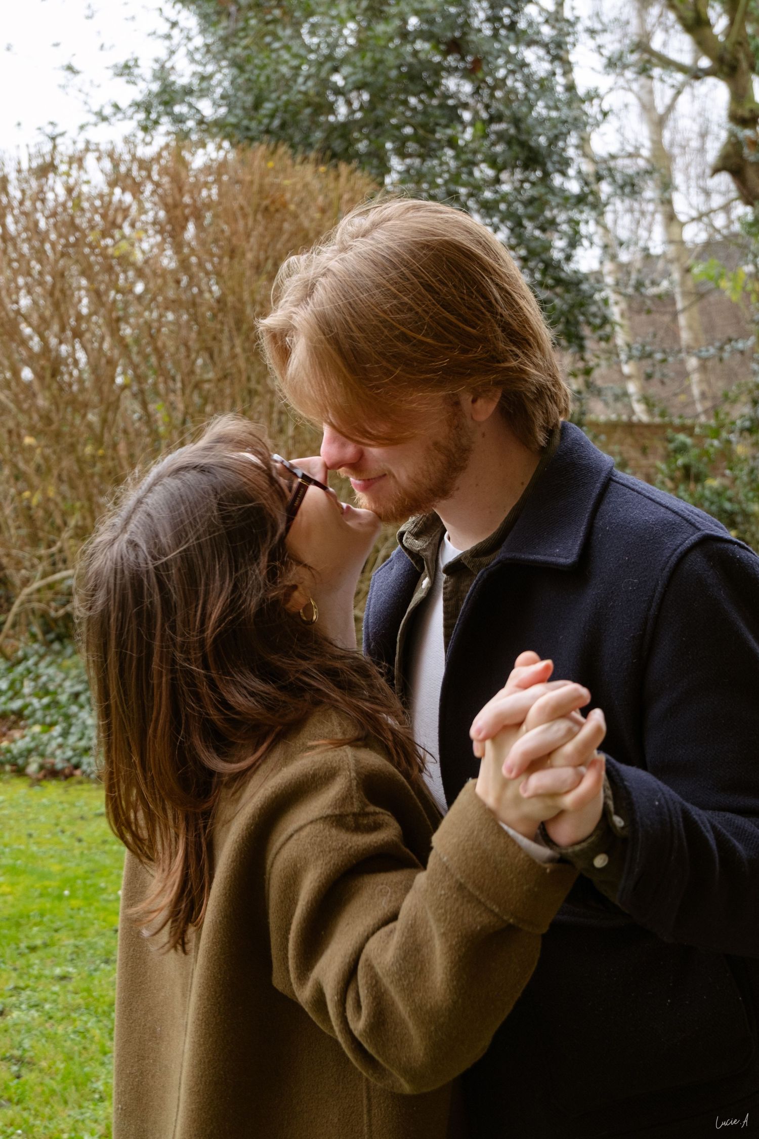 Un couple danse enlacé dans un jardin, se tenant la main et partageant un moment d'intimité en plein air, en hiver.