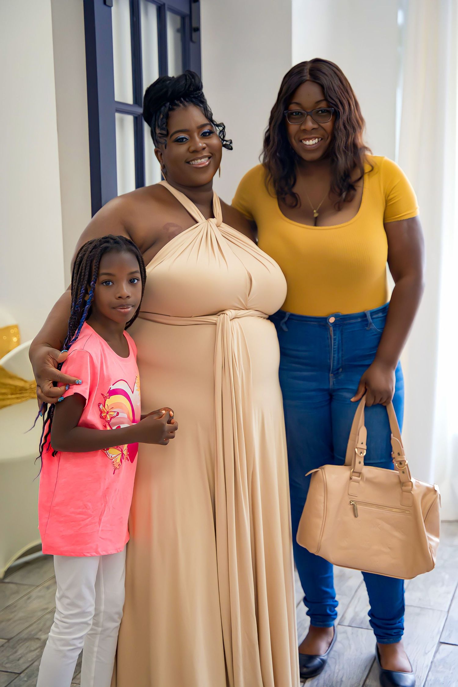 Three generations of women smiling together at a special celebration, wearing colorful outfits.