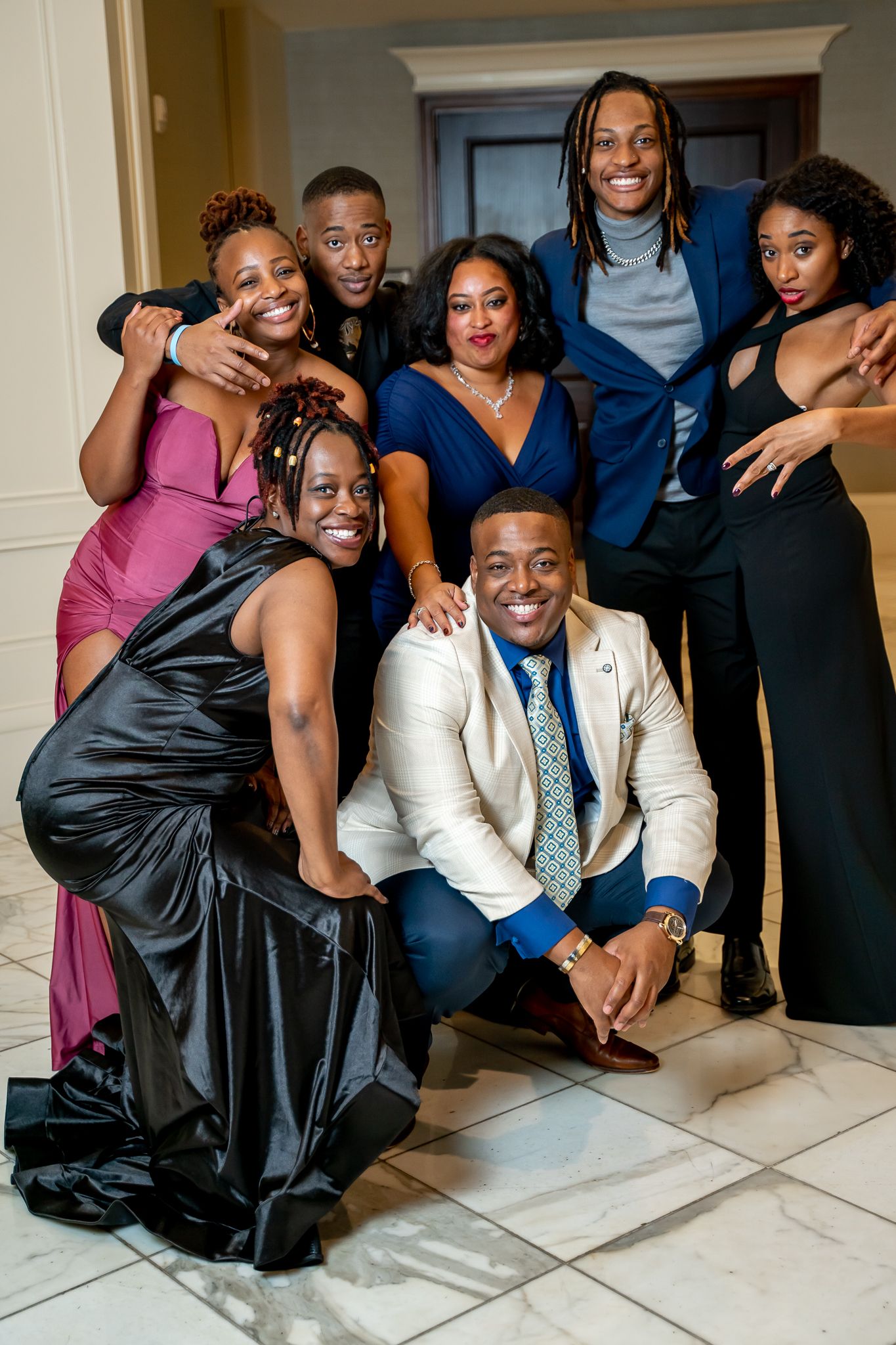 Group of friends in formal wear sharing laughs while posing at an elegant event.