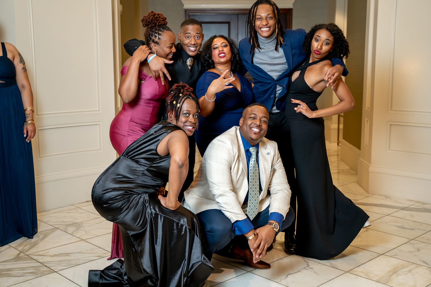 Joyful group of dressed-up friends striking fun poses at a formal gala.