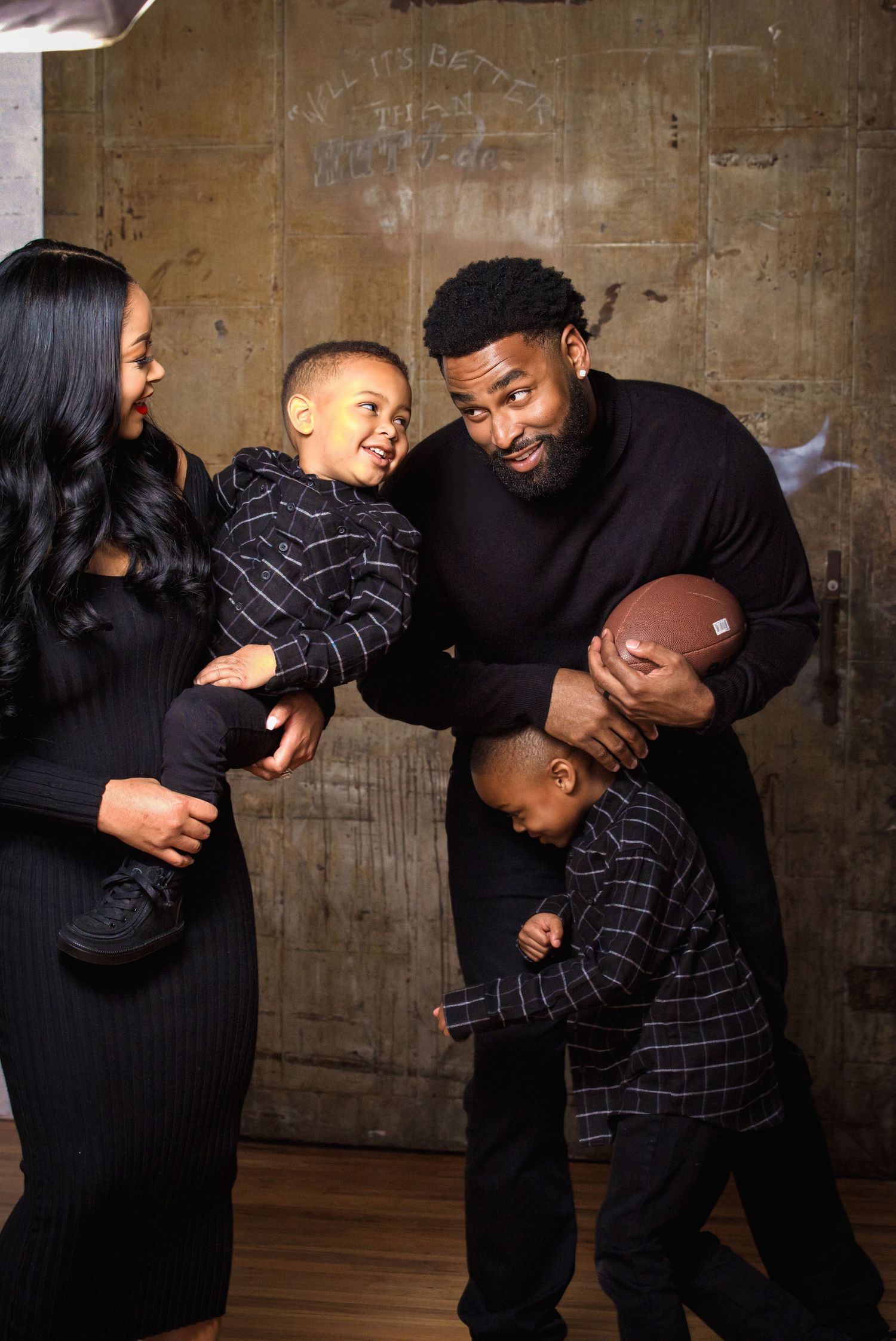 Happy Black family of four in coordinating black outfits sharing a playful moment together.
