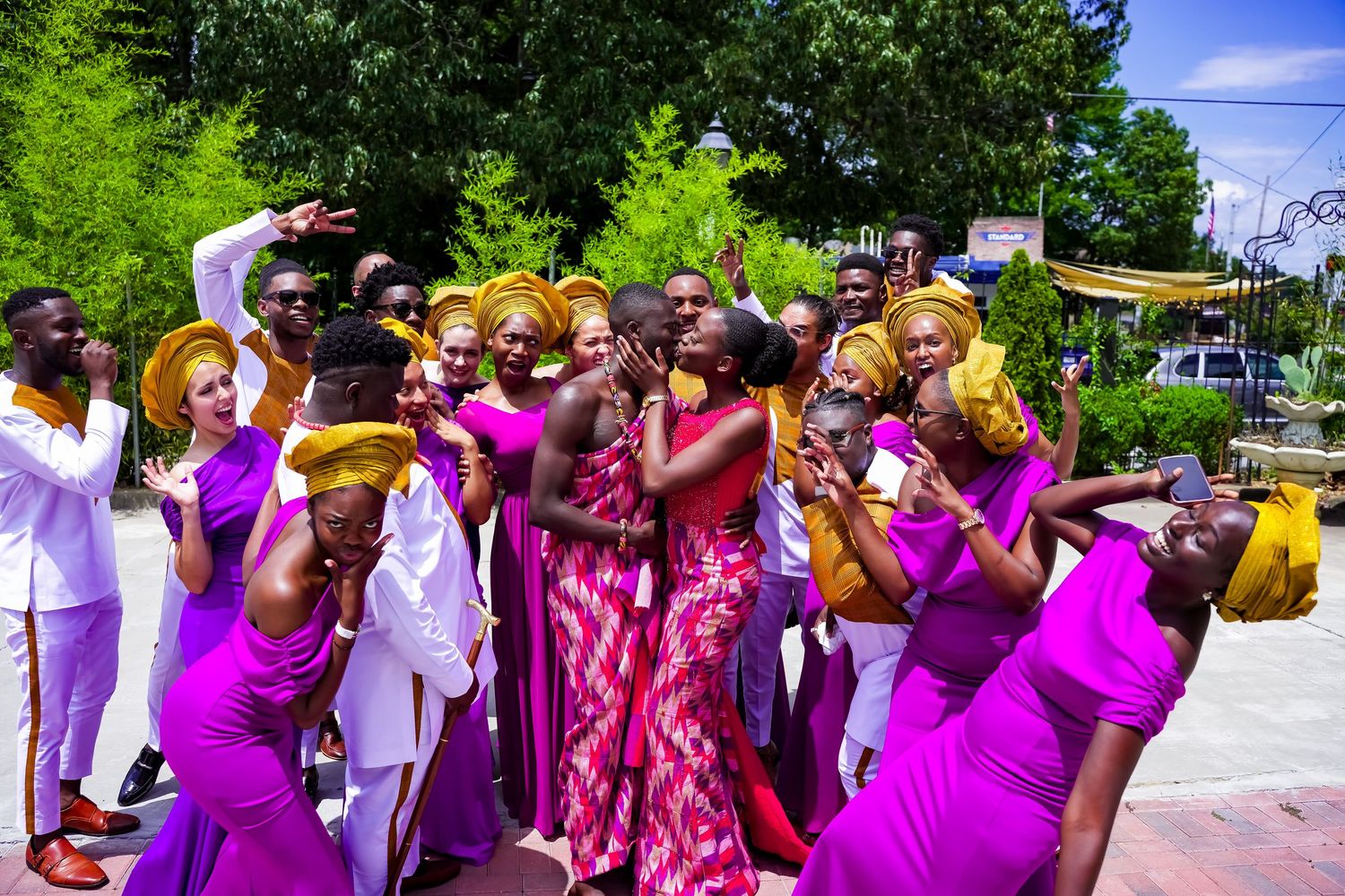 A lively group of people in bright purple and gold traditional African outfits celebrating together.