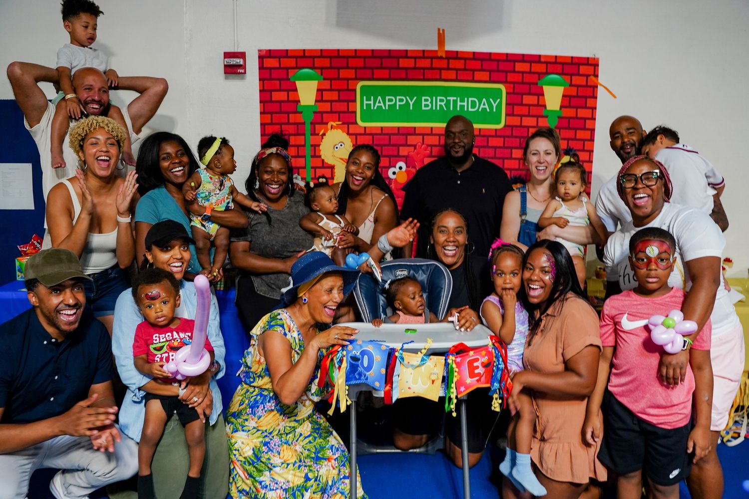 Large diverse family group celebrating a childs birthday with Sesame Street decorations.