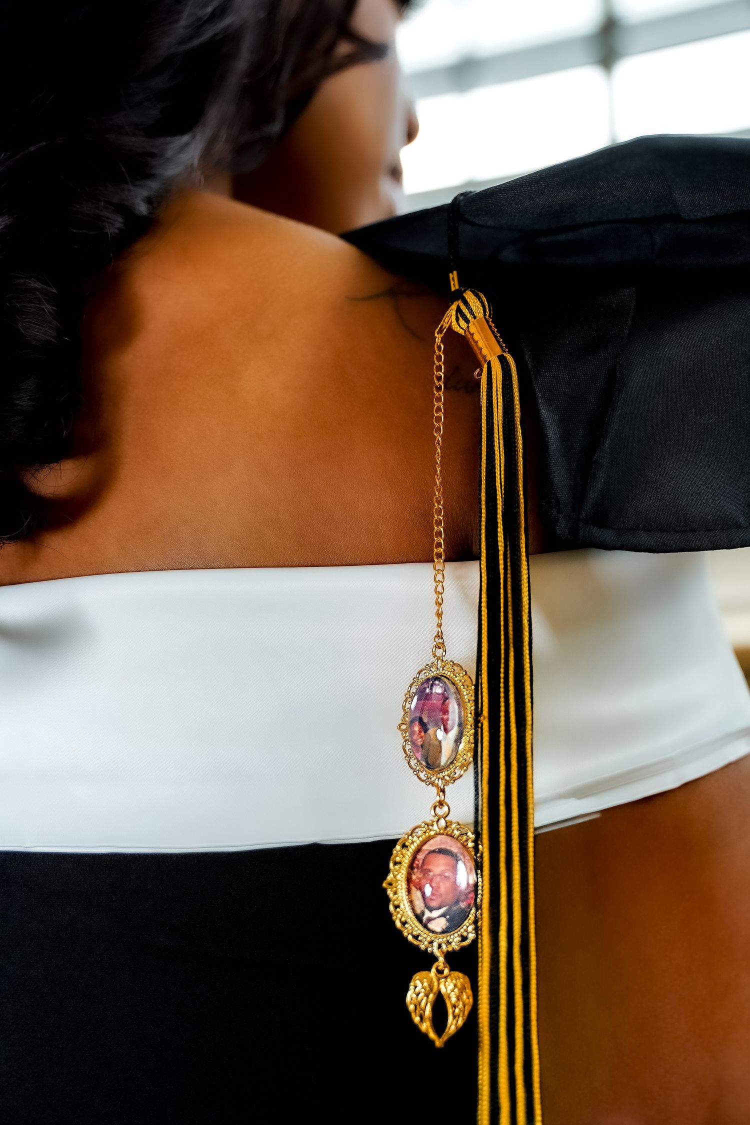 Close-up of graduation cap tassel with gold photo charm pendant on graduate.