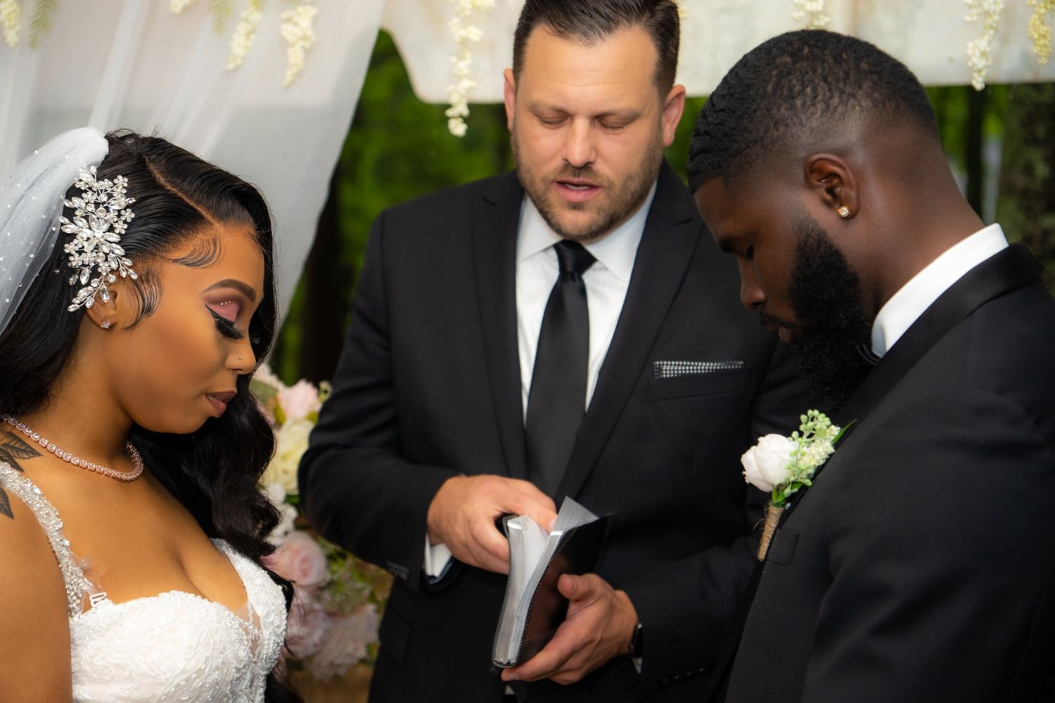 Officiant reads vows as bride in white gown and groom in black suit stand at altar.