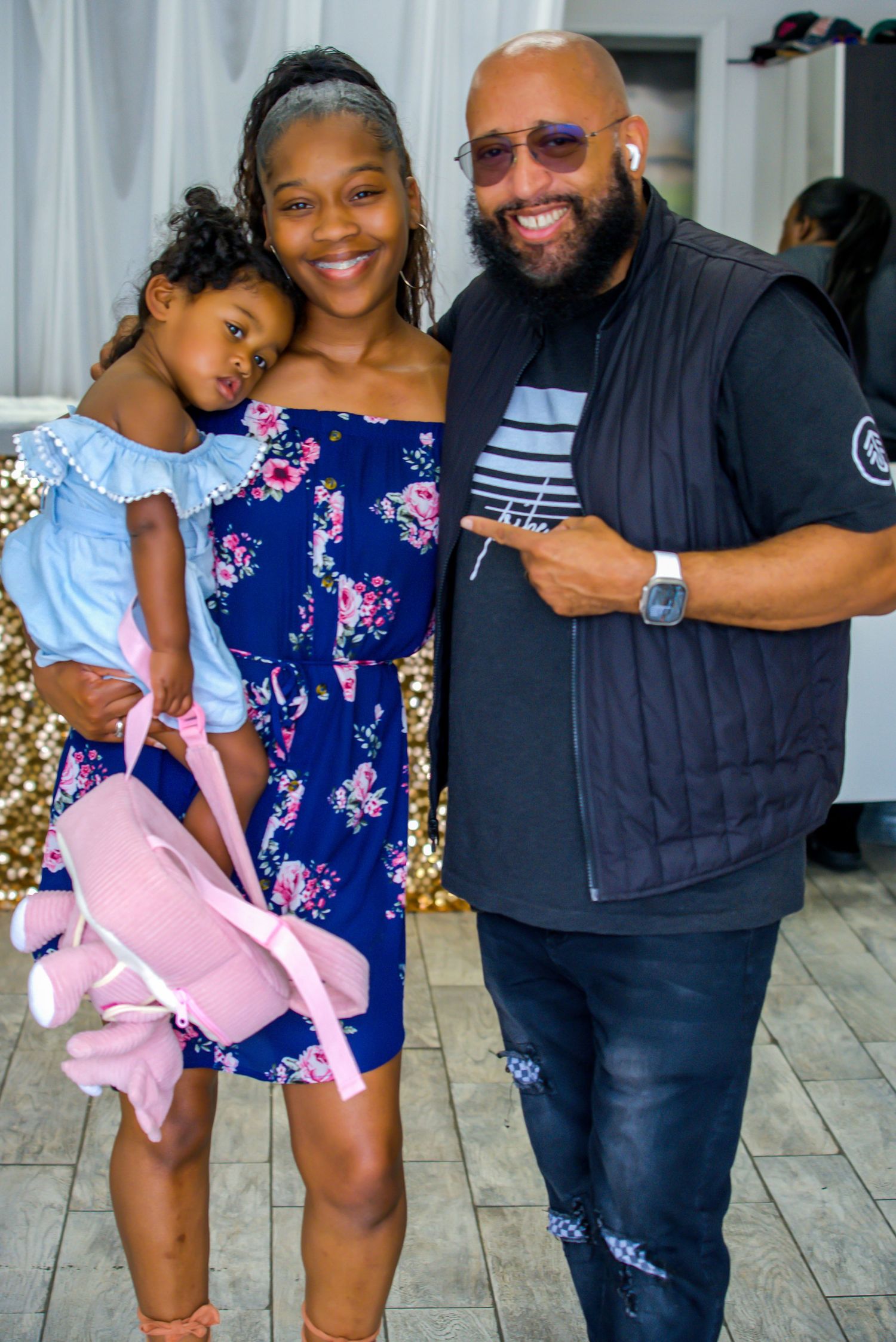 Happy family with young girl in blue dress poses together at an indoor celebration event.