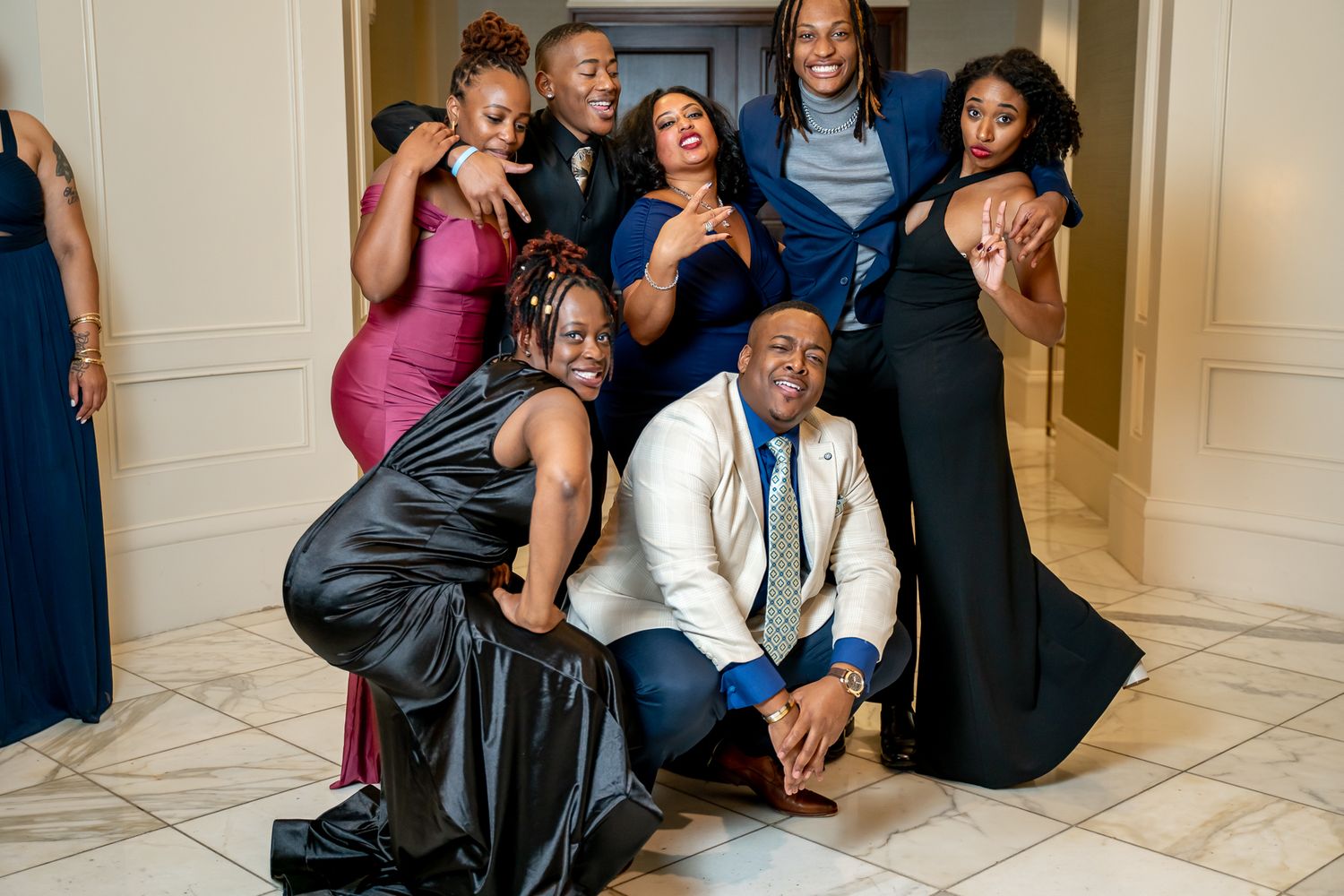 Laughing group of elegantly dressed friends posing for photos at a formal event.