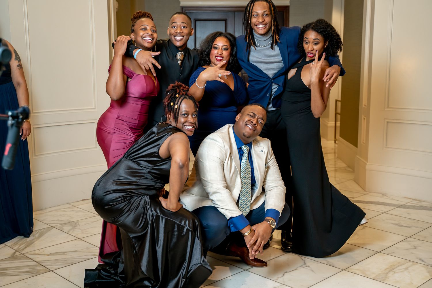 Cheerful group of friends in formal attire striking playful poses at a gala.