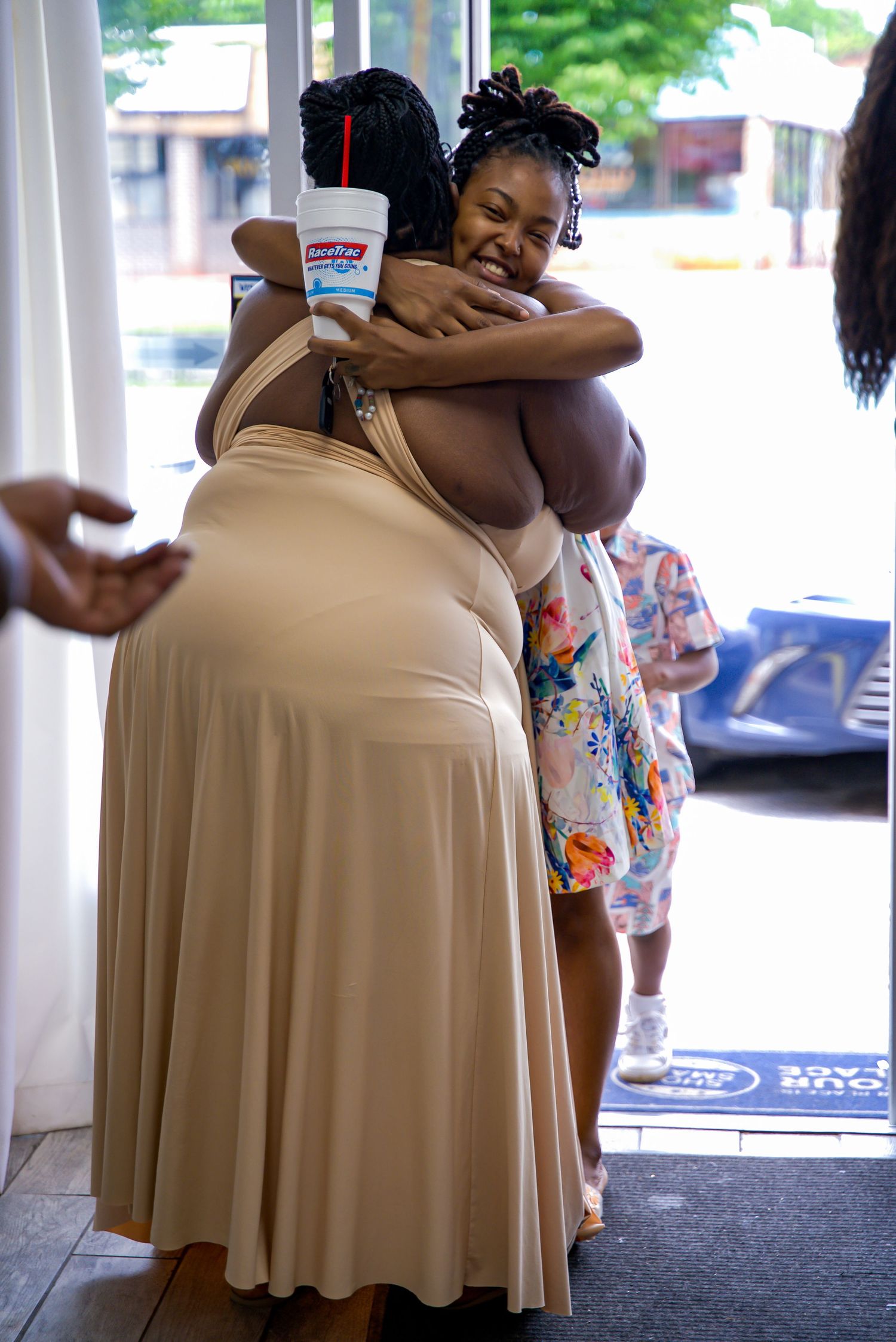 Two women sharing a warm hug near a glass door entrance at an event.