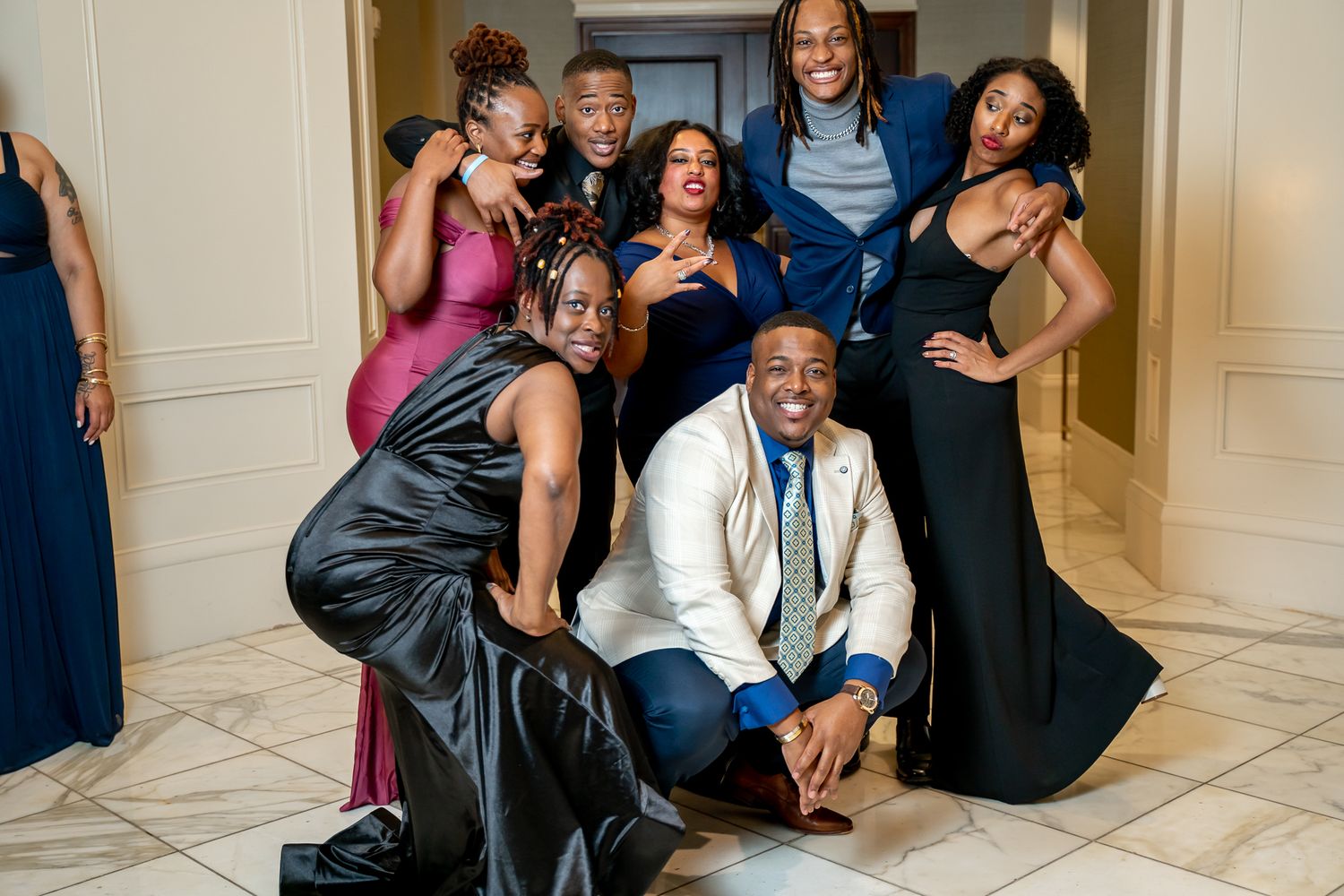Group of friends posing playfully in formal attire at an elegant event.