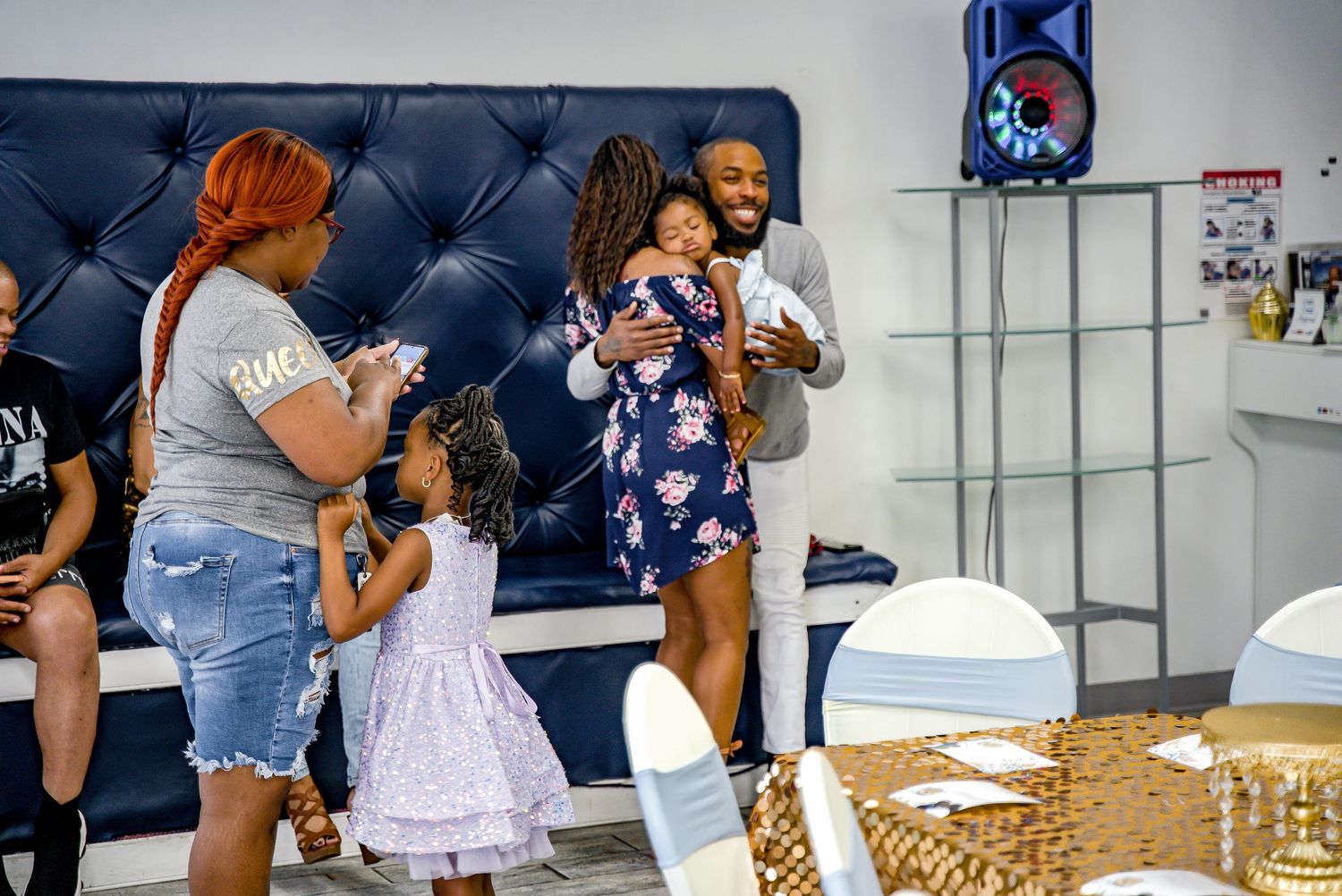 Family group sharing joyful moment with baby at decorated indoor celebration event.