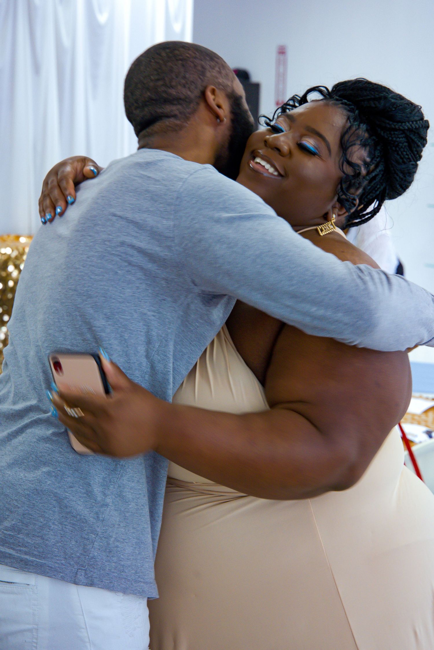 Two people sharing a warm embrace and smiling at an indoor celebration event.