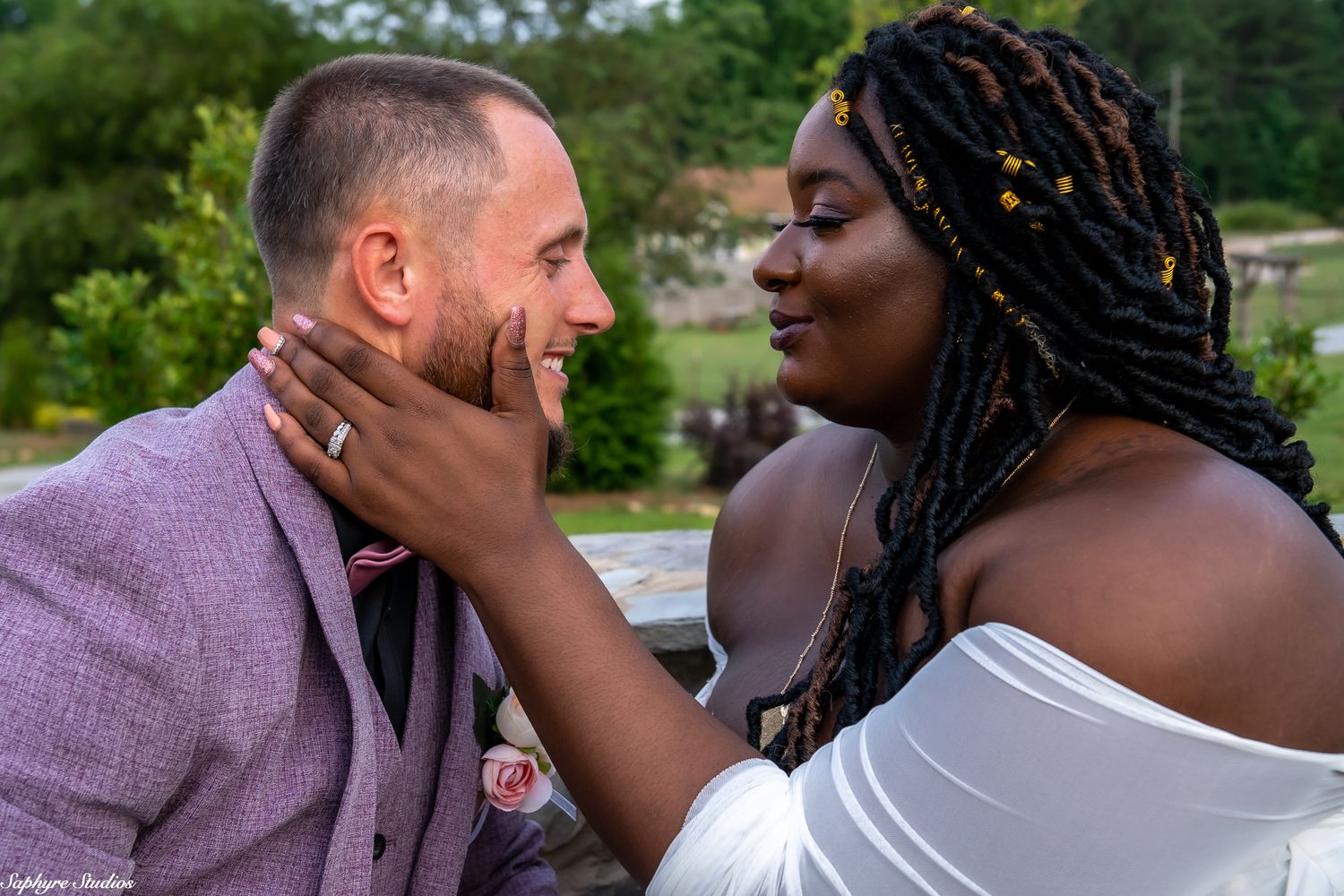 Interracial couple shares a tender moment, bride touching grooms face lovingly at their wedding.