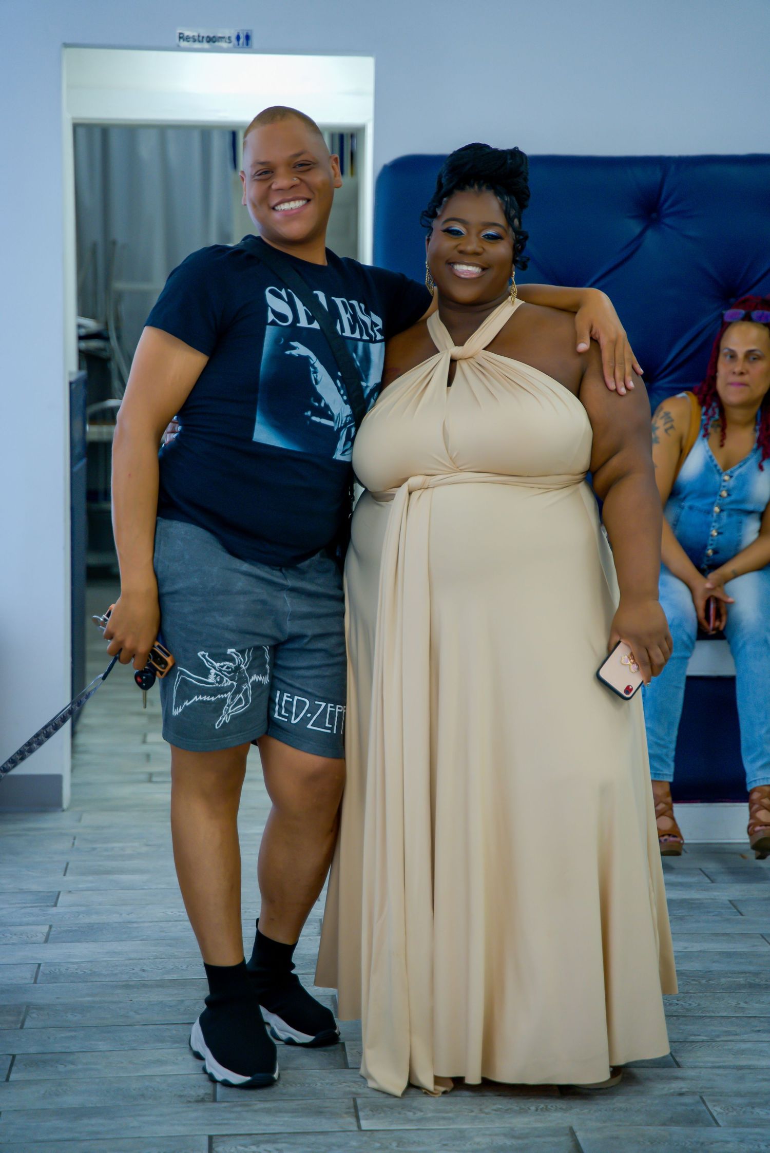 Two people smiling and posing together indoors at a special occasion event.