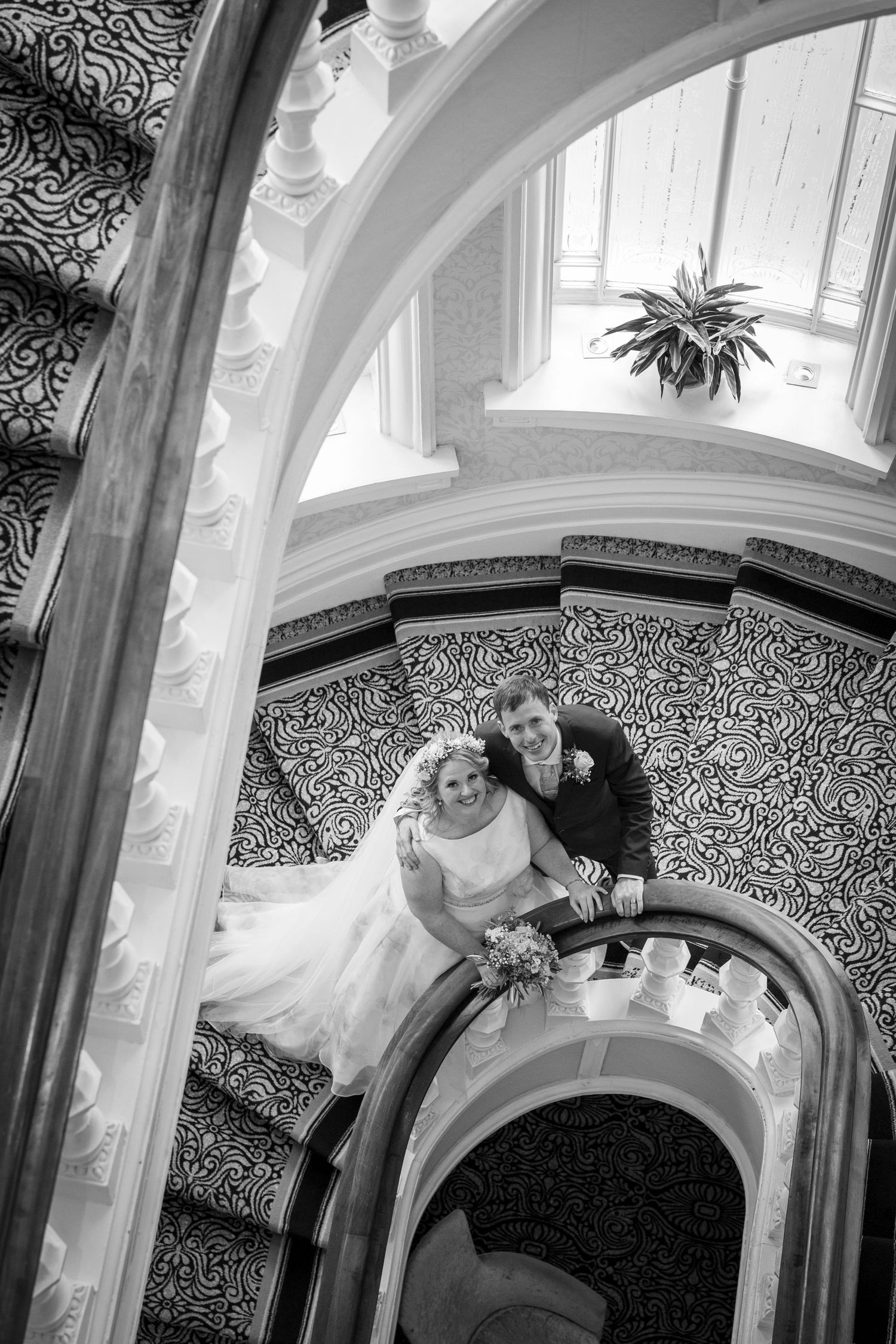Bride and groom on grand staircase at The Grand Tynemouth, black and white wedding photo, elegant spiral stairs, romantic moment