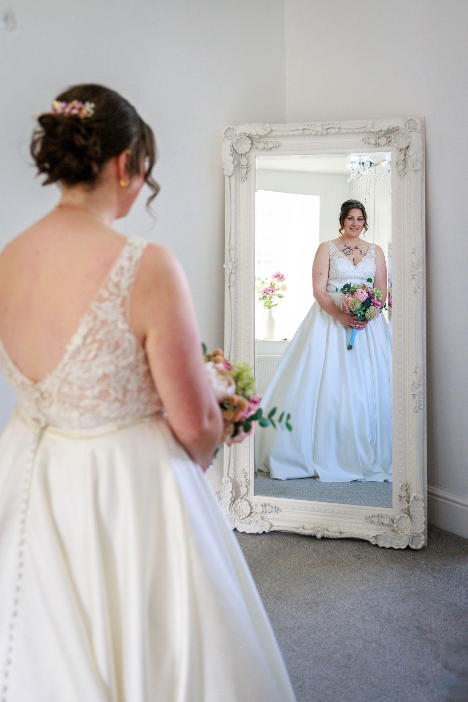Bride views her reflection at Danby Castle, bouquet in hand; calm, elegant pre-ceremony moment.