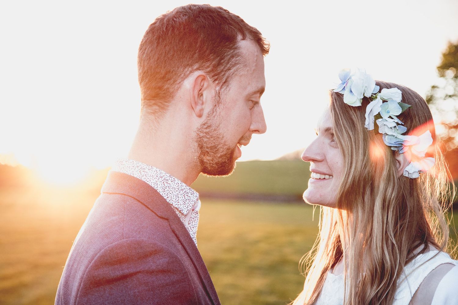 Bride and groom face each other at sunset; warm light and soft glow create a romantic moment.Richmound