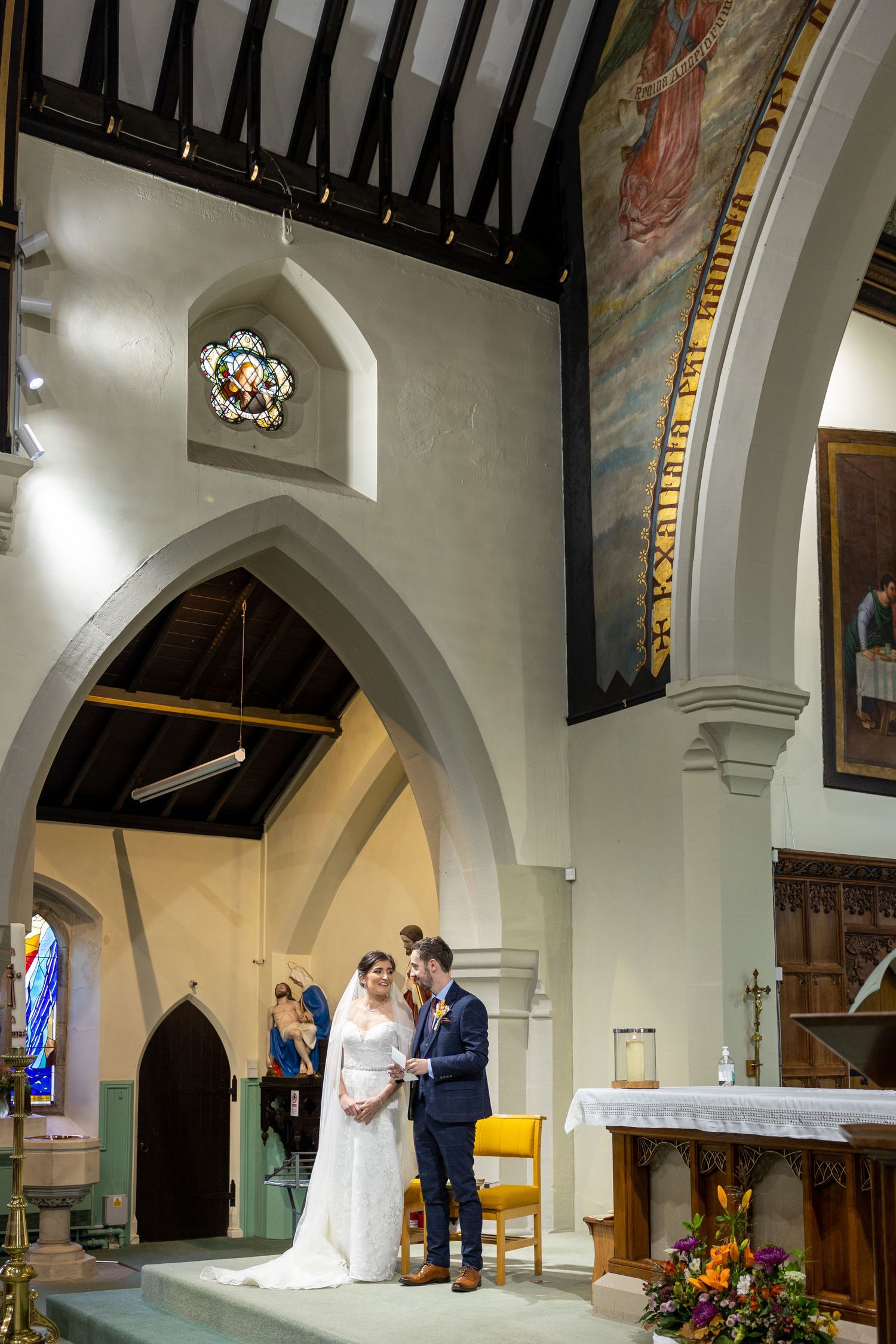 Bride and groom share a quiet moment at the altar beneath grand arches, capturing a timeless church wedding scene full of emotion.