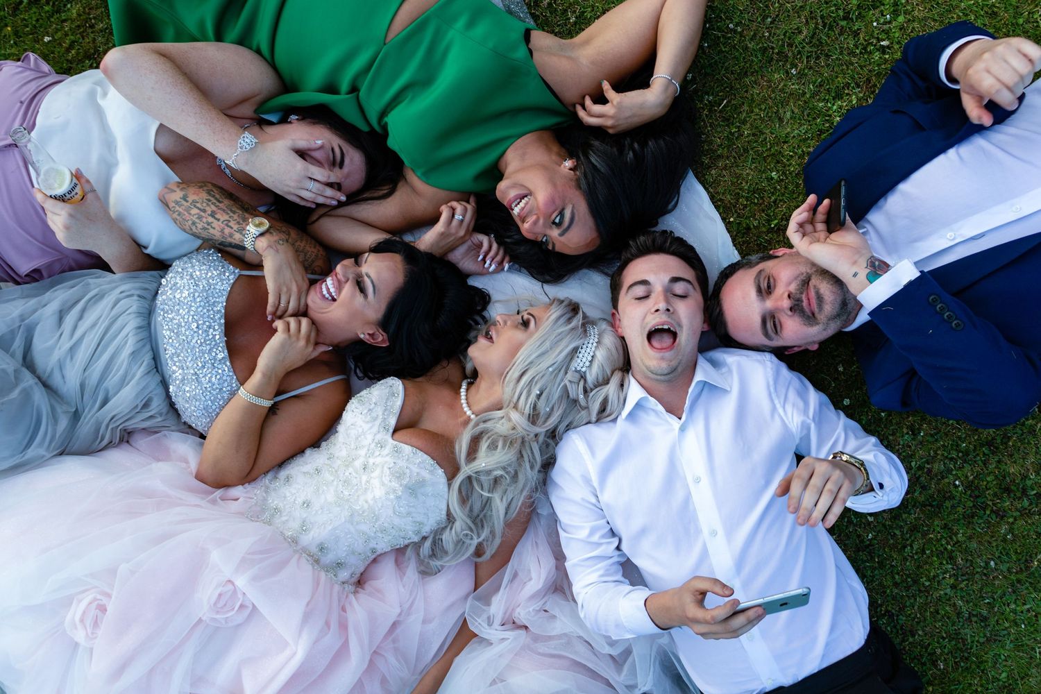 Fun wedding group moment at Wynyard Hall with guests relaxing and laughing on the grass