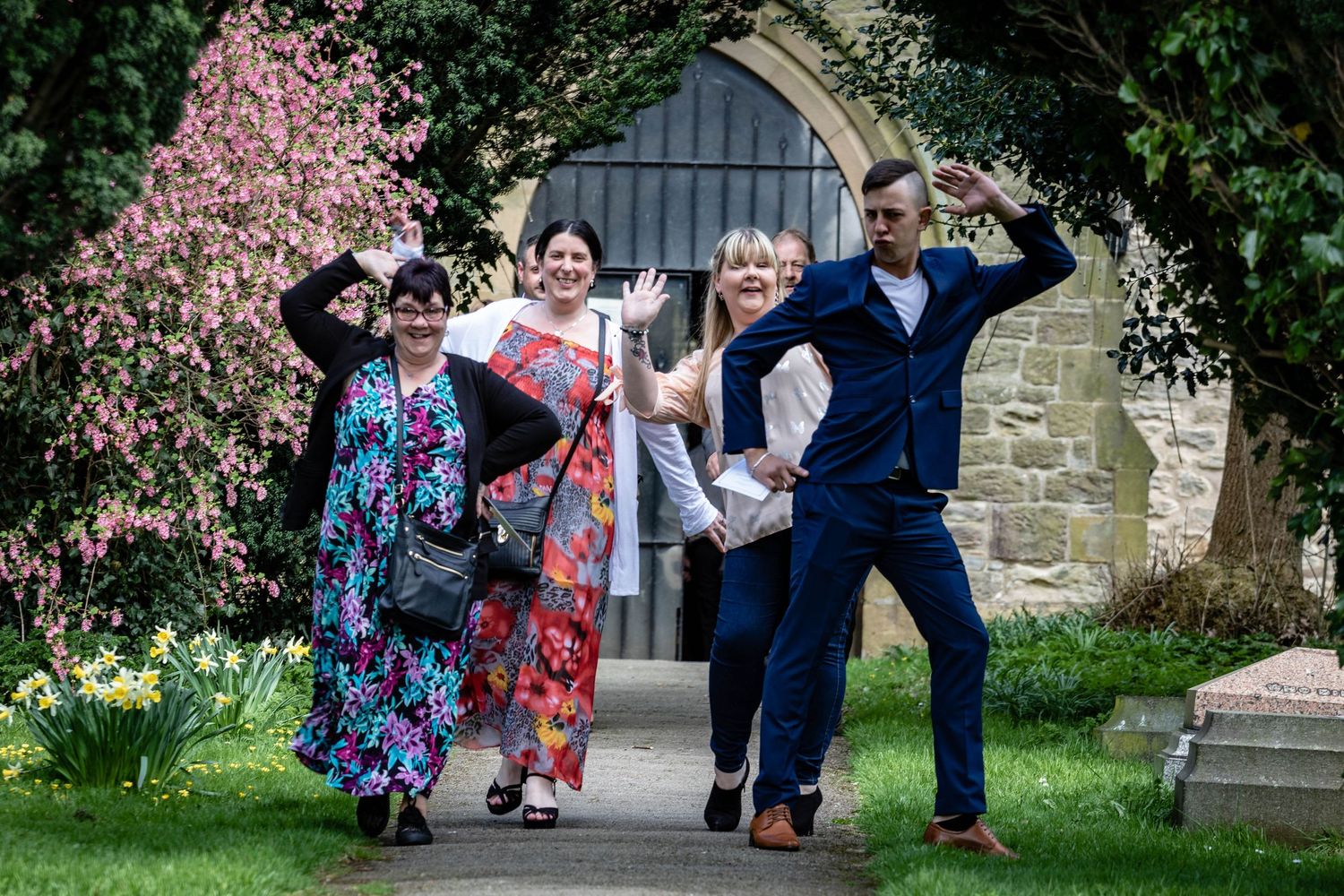 Wedding guests having fun outside Houghton-le-Spring church, County Durham, playful group portrait with joyful expressions and lively atmosp