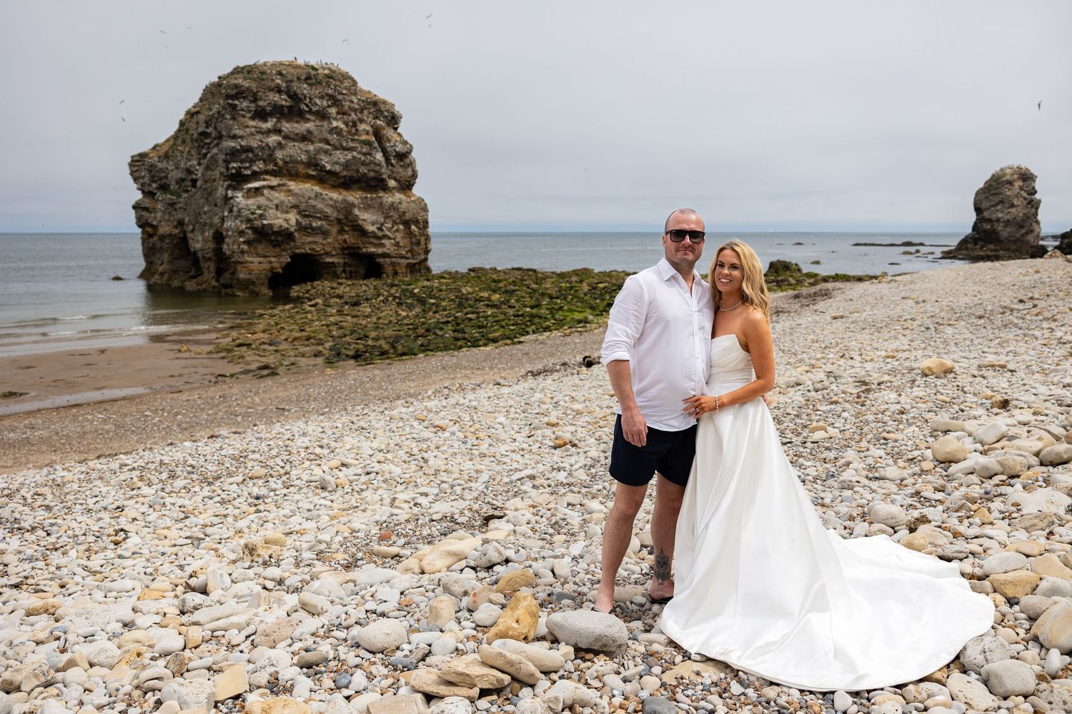 Couple on rocky beach by Marsden Rock, The Grotto, South Shields; rugged coastal backdrop.