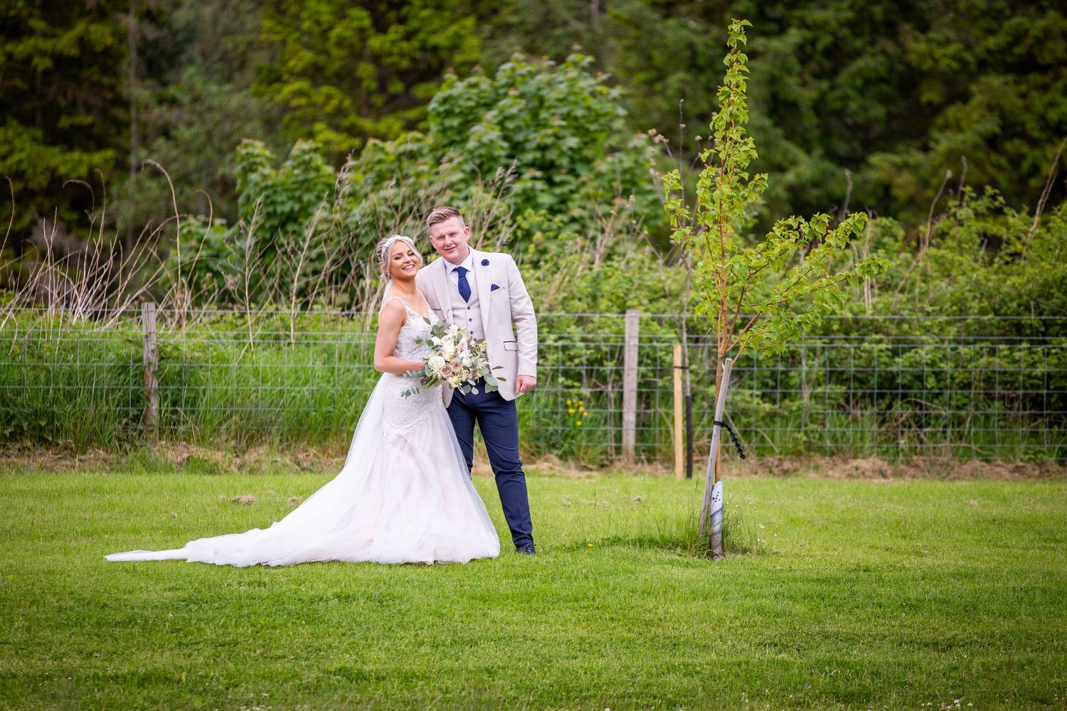 Bride and groom portrait outdoors in countryside setting, relaxed wedding photography, natural greenery backdrop, romantic newlywed moment