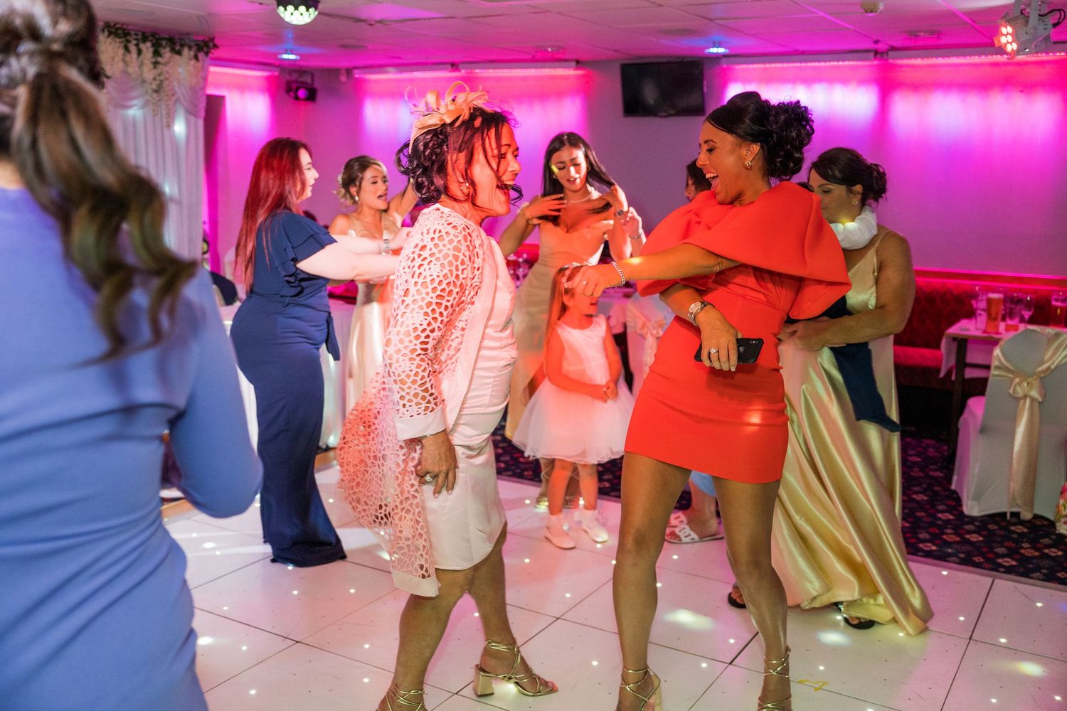 Wedding dance floor party with guests dancing under colourful lights, fun reception atmosphere, lively UK wedding celebration moments