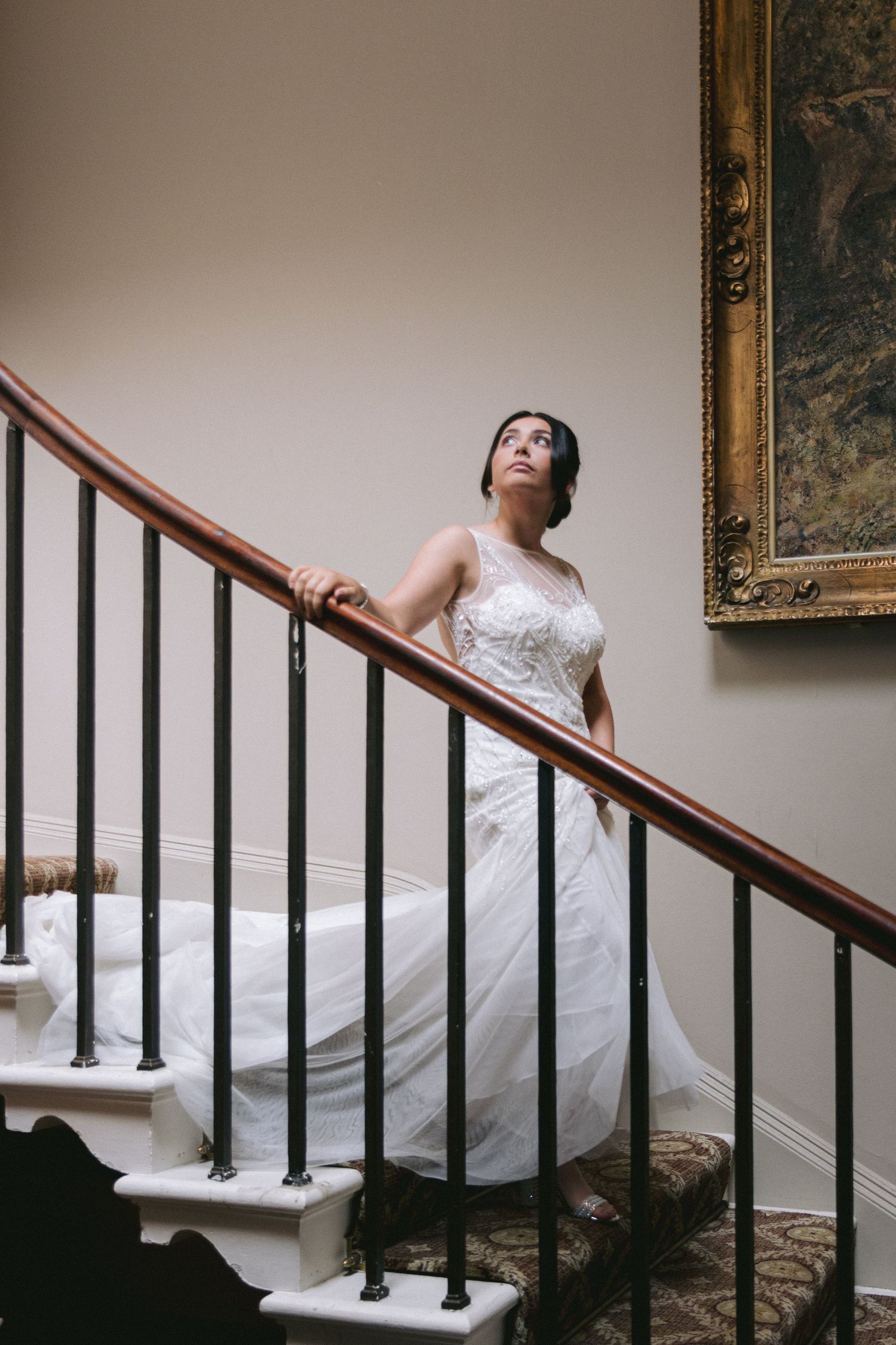 Bride on staircase; elegant portrait with soft light, classic railing, and timeless interior details.