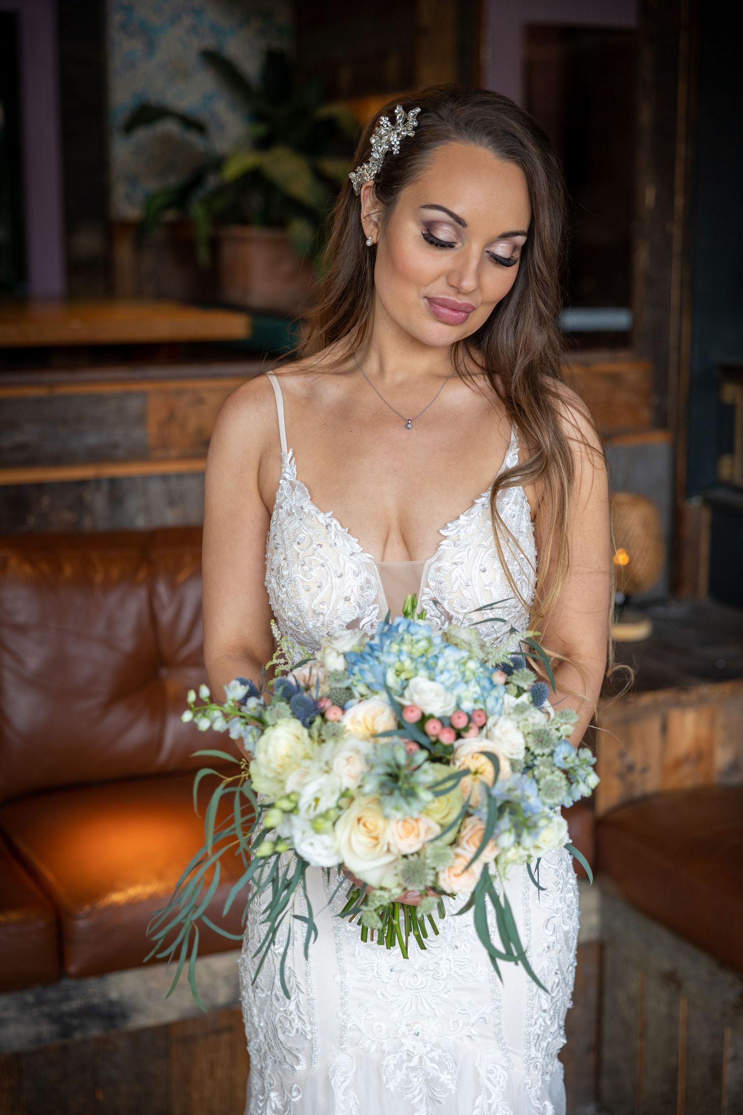 Bride holds bouquet; soft, intimate portrait with natural tones and relaxed indoor setting.