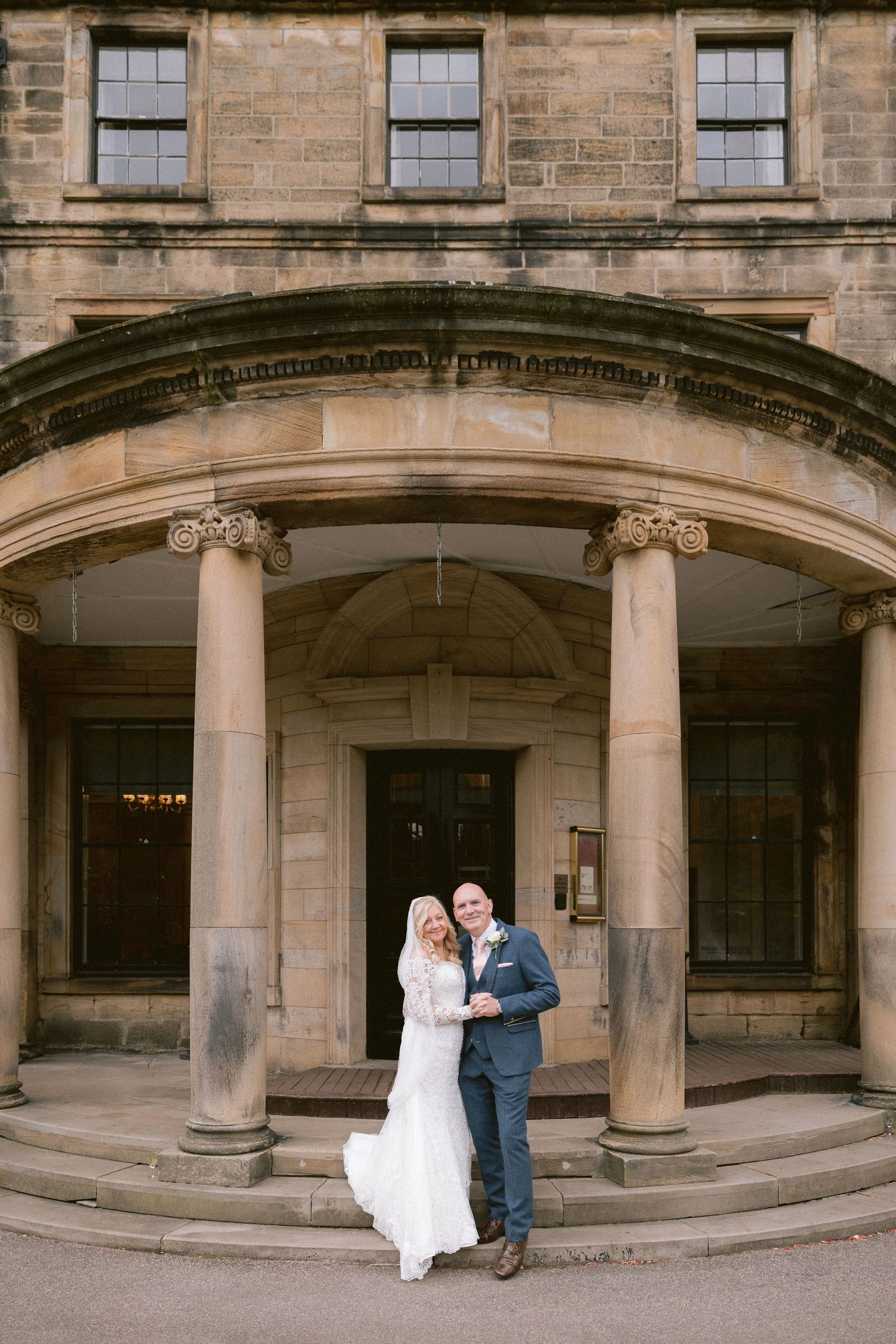Bride and groom outside Beamish Hall Hotel, elegant wedding portrait beneath grand columns at historic country house venue