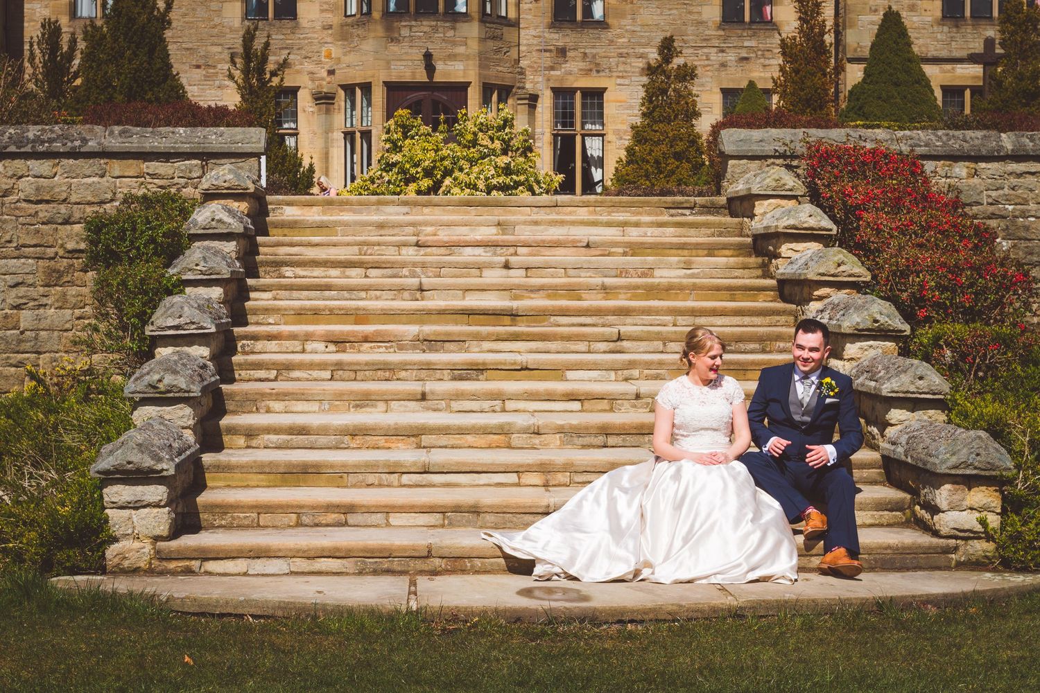 Bride and groom sitting on stone steps at Slaley Hall wedding venue in Northumberland