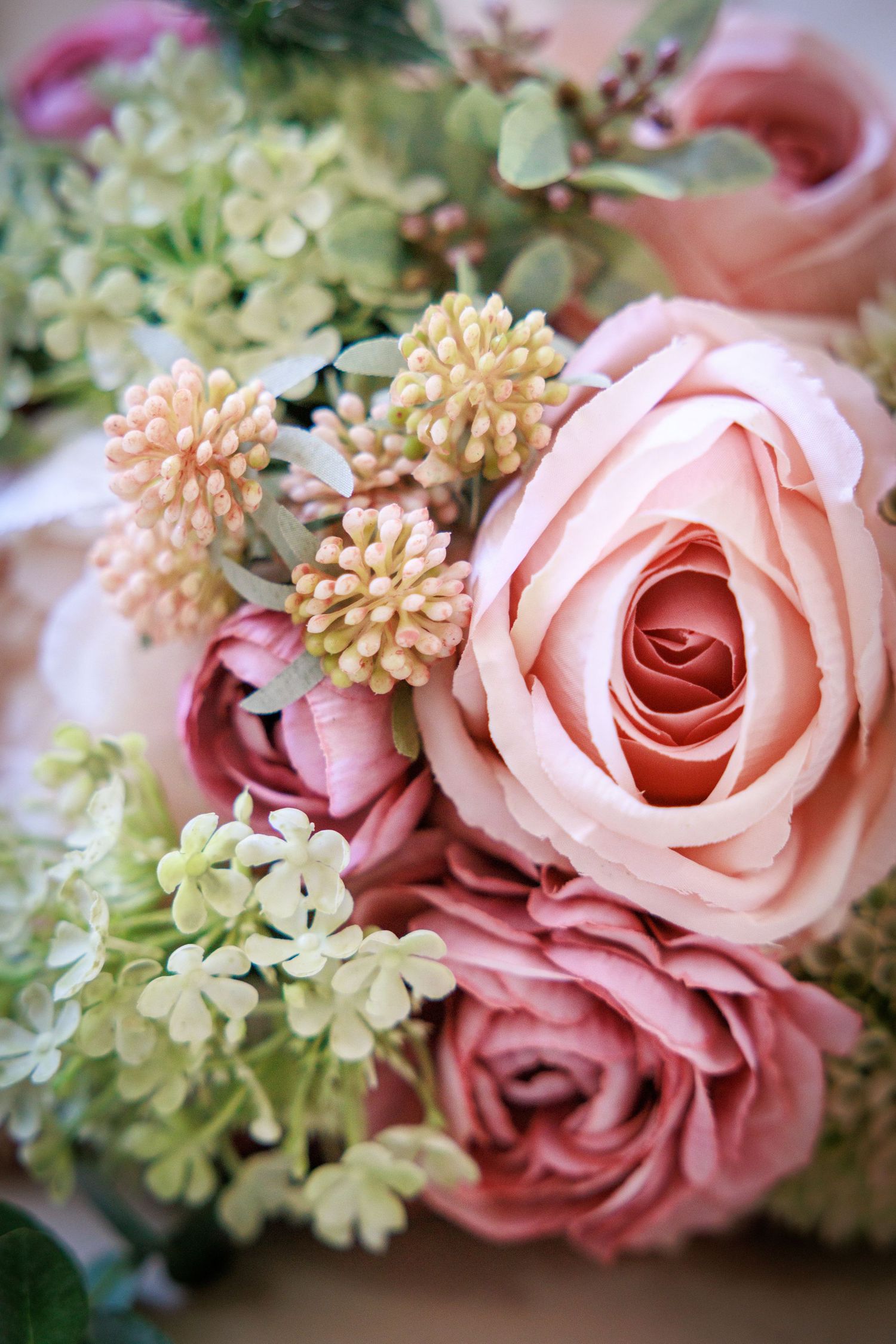 Soft pink roses with delicate greenery; elegant bridal bouquet detail with romantic pastel tones.
